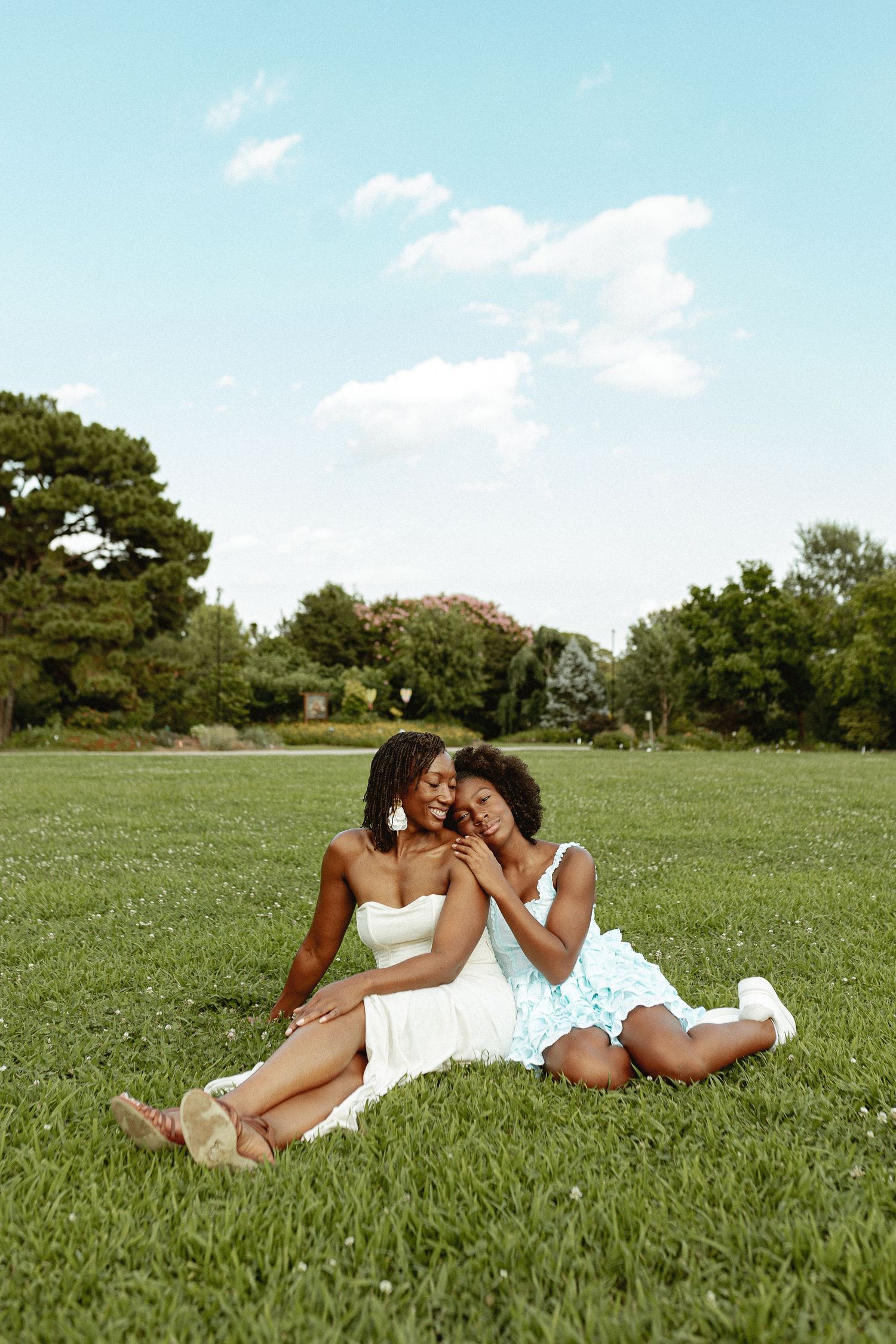 Two people sharing a joyful moment while relaxing on grass in a sunny park.