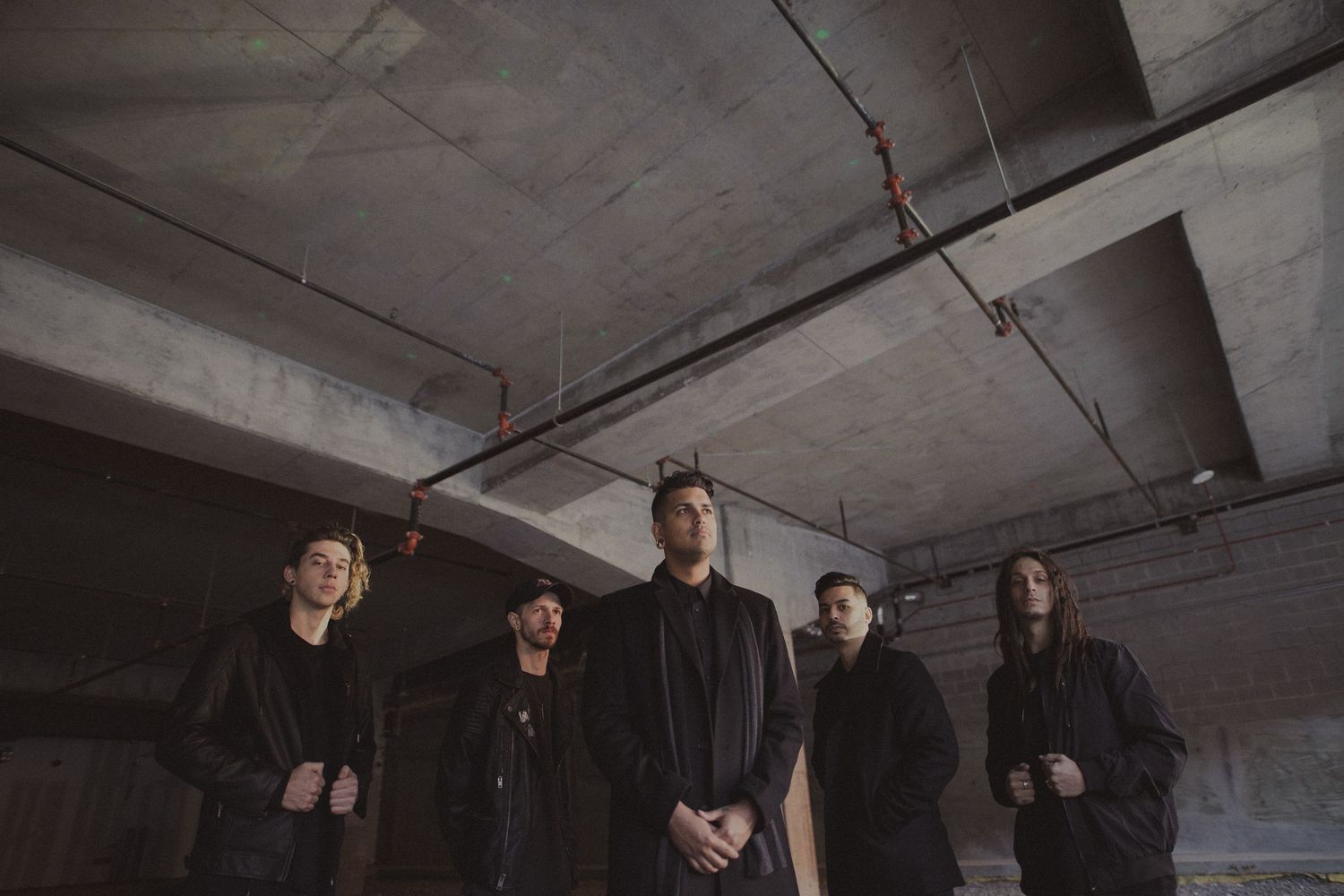 Group photo of band members standing against an industrial concrete background.