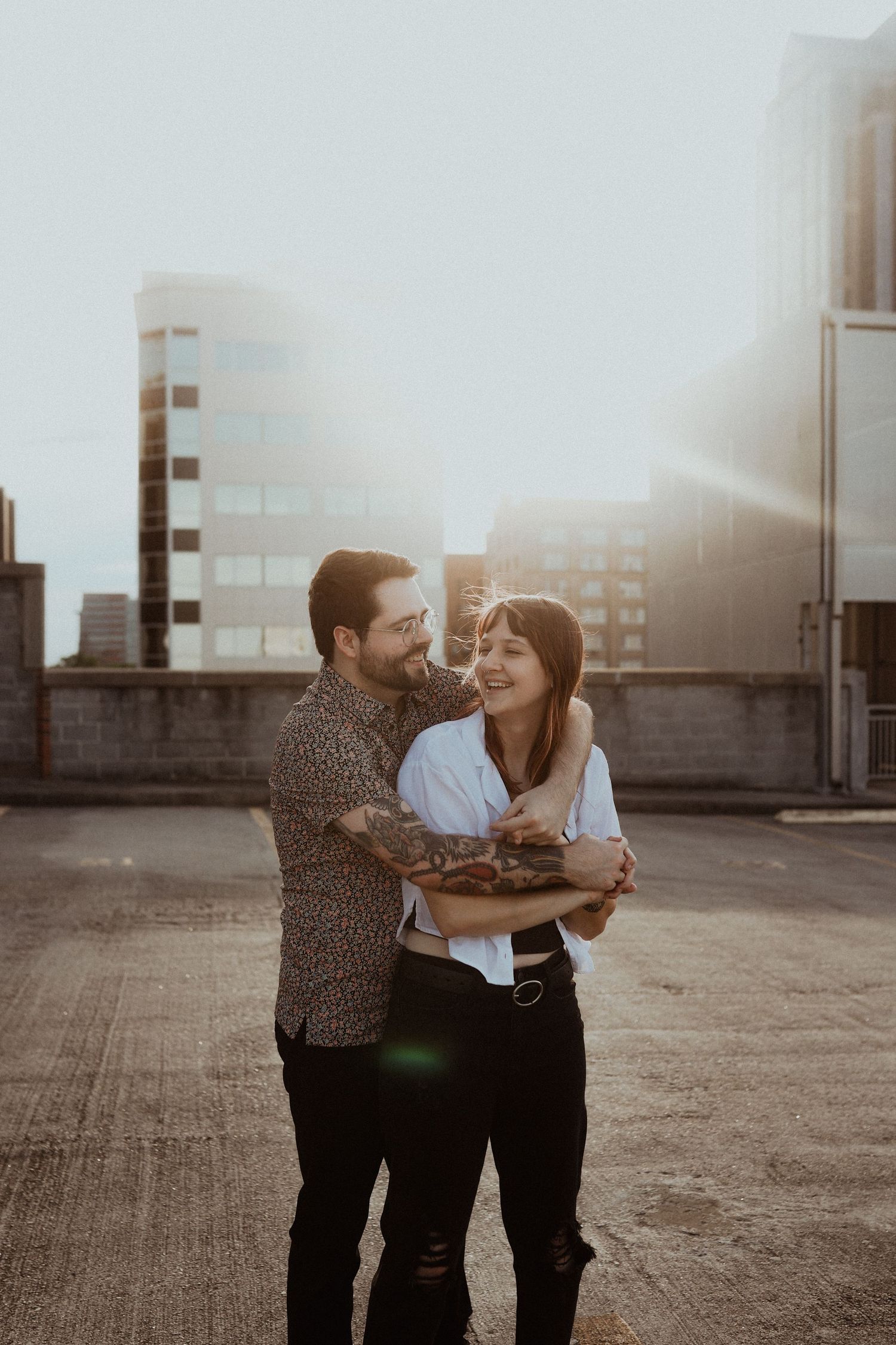 A couple dances and laughs together during a sunset rooftop photoshoot.