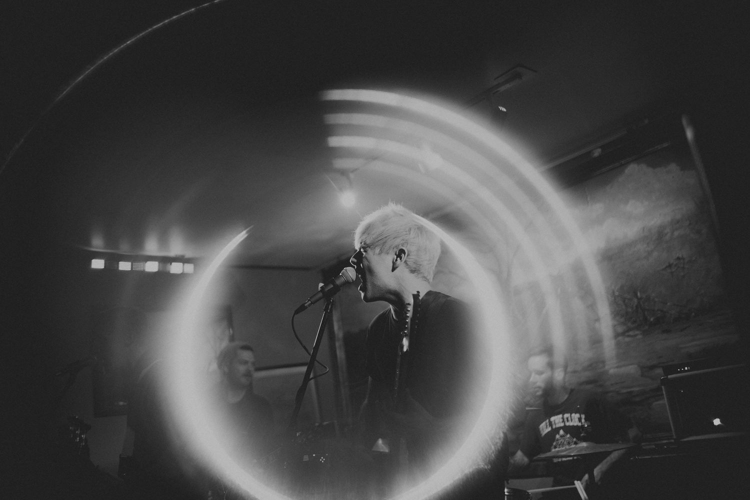 Concert performer in dramatic circular light effect on dark stage.