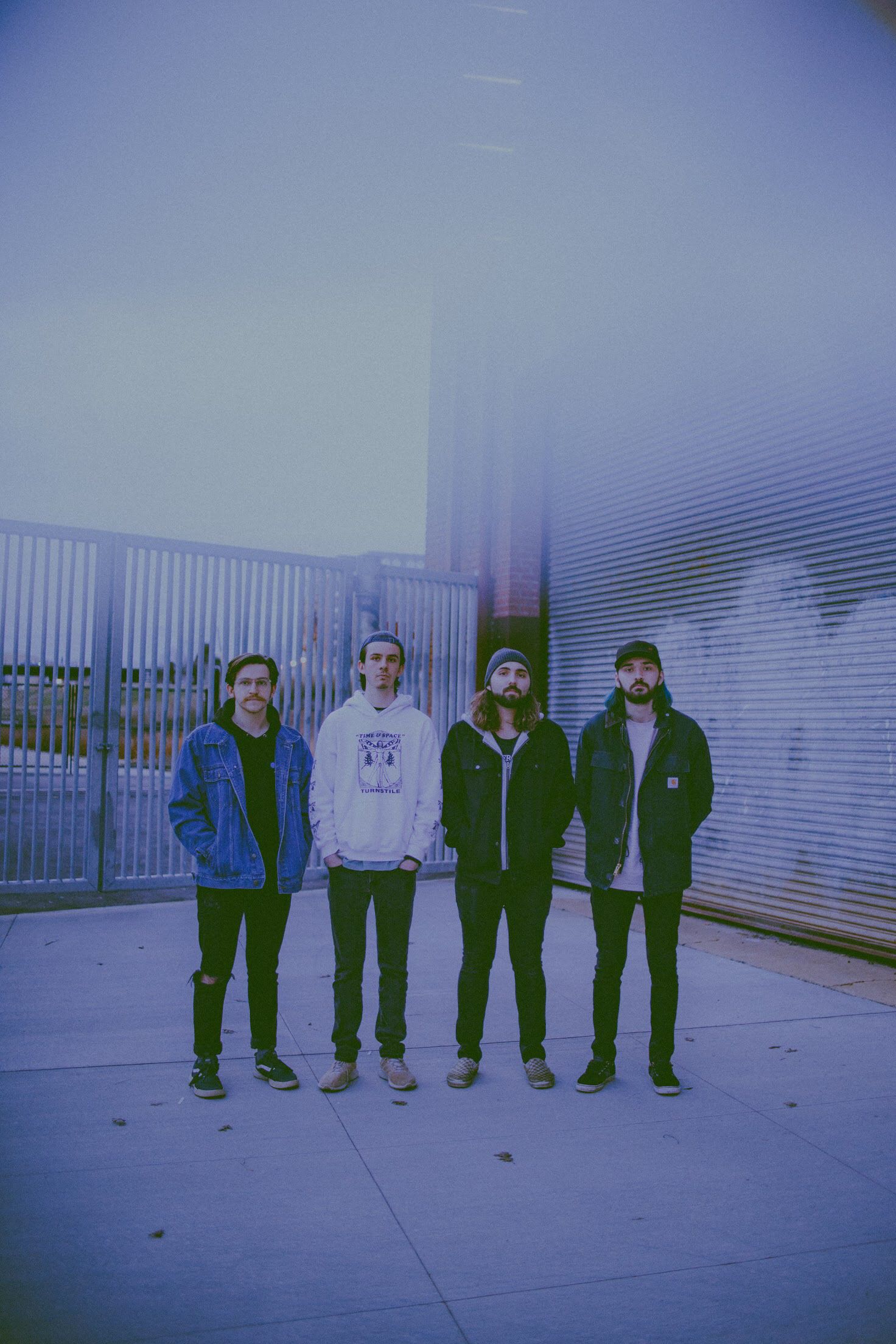 A group of people in casual clothing stand against a blue-tinted wall in a sequence of similar poses.
