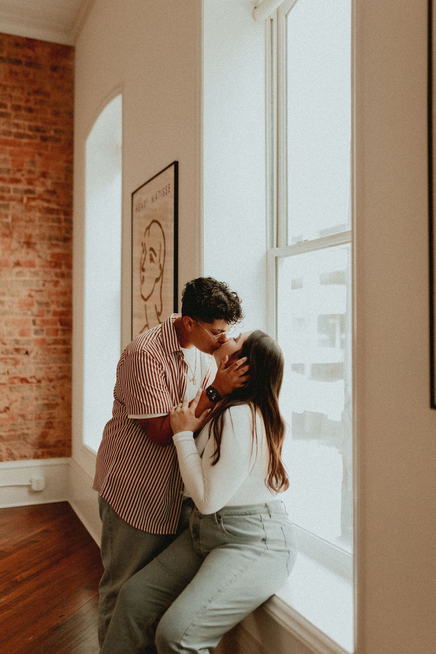 An intimate moment captured in a bright room with exposed brick walls and hardwood floors.