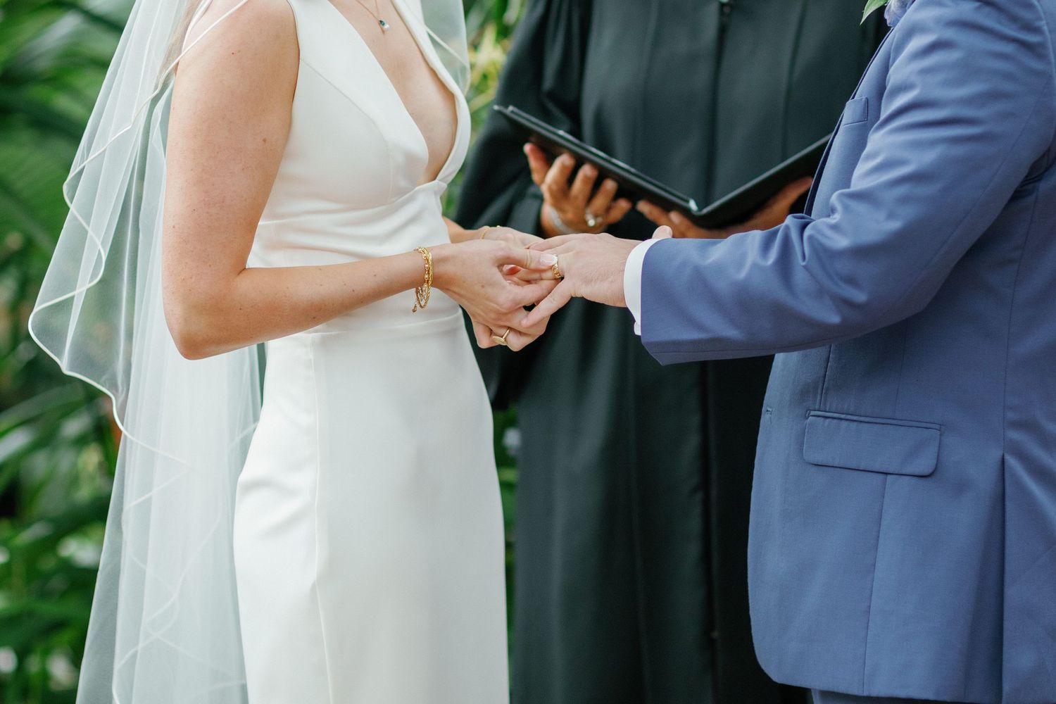 Bride putting ring on grooms hand at wedding