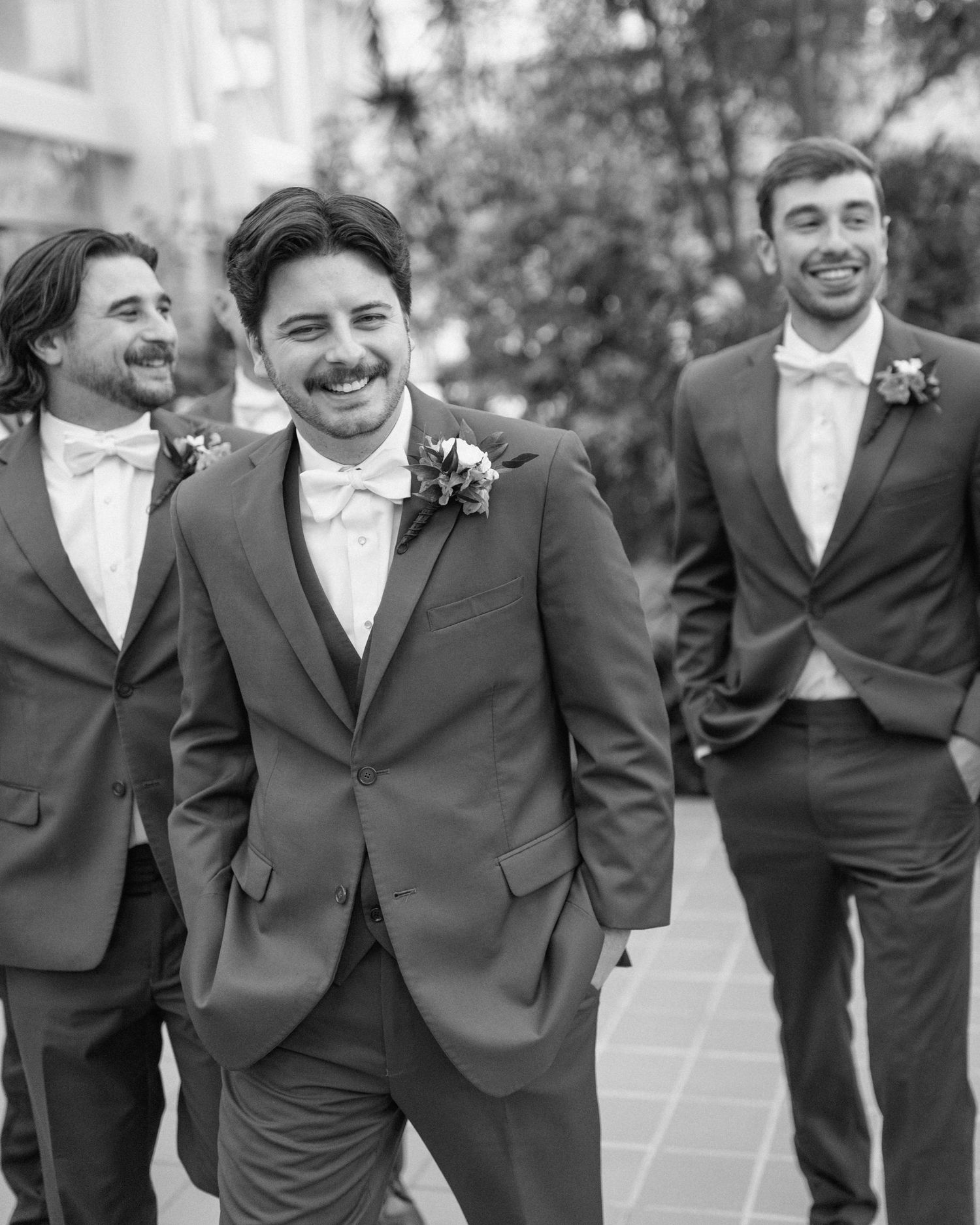 Candid photo of groom laughing while walking with groomsmen
