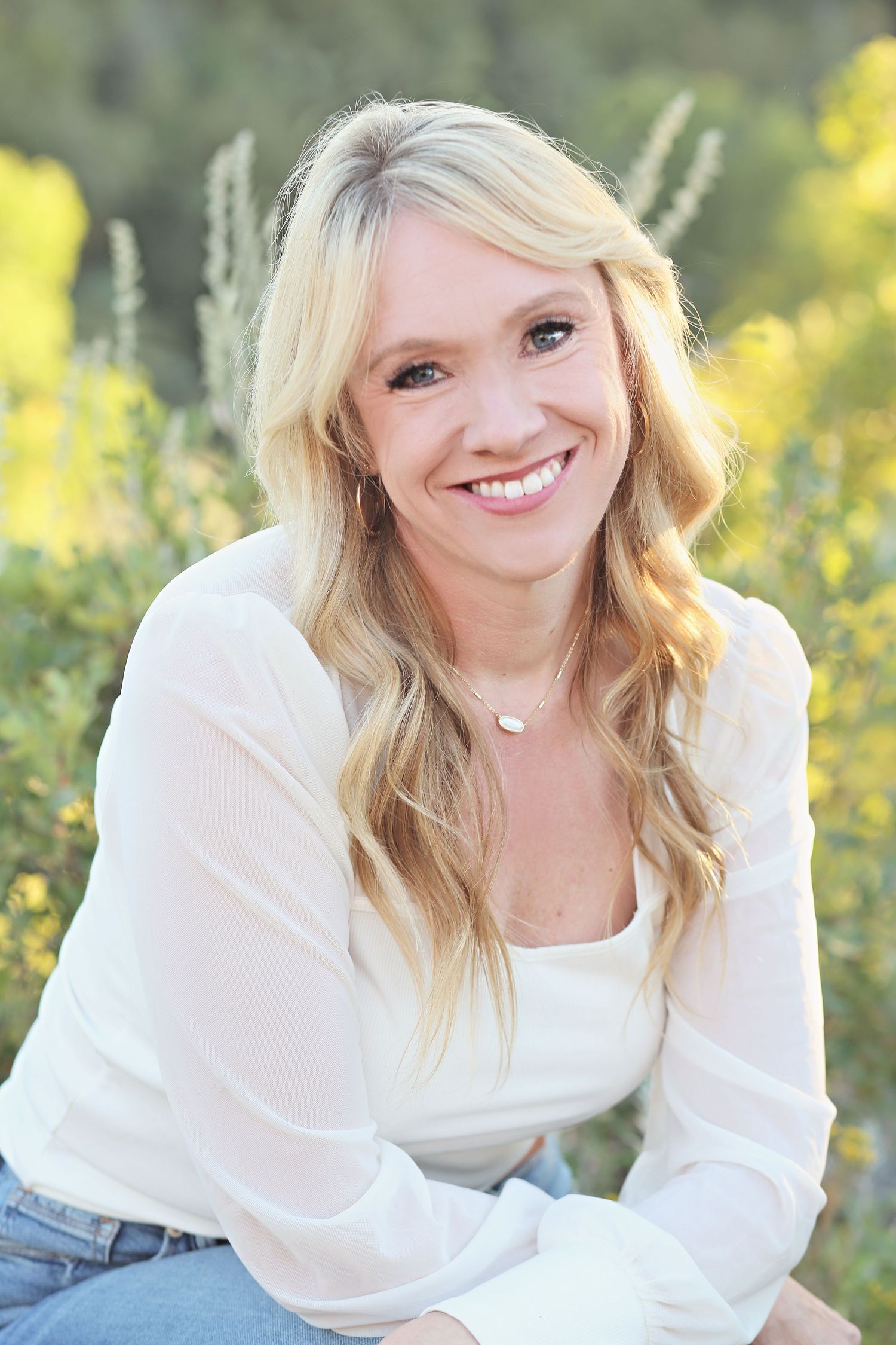 A portrait in a field of yellow wildflowers with soft natural lighting.