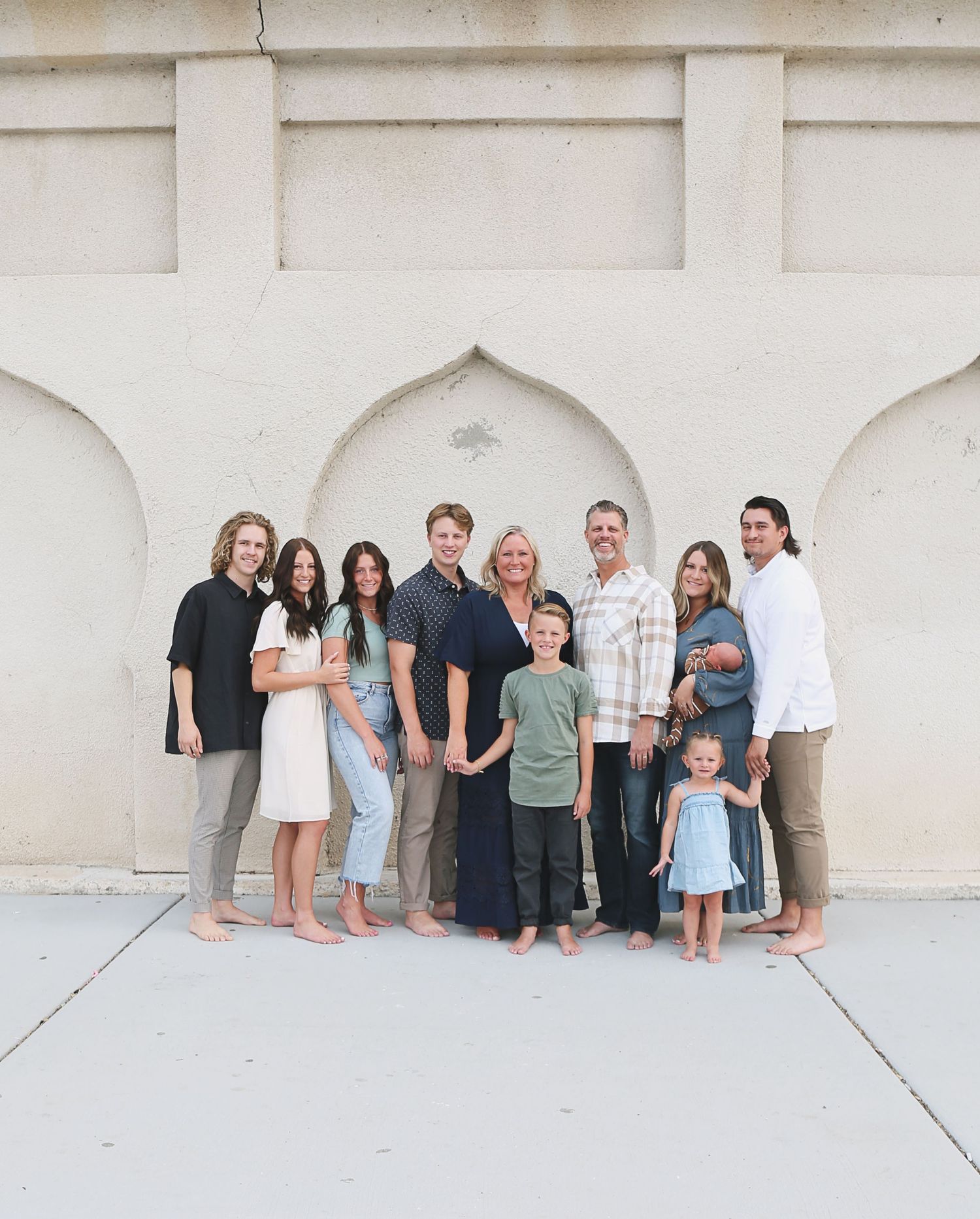 A large extended family group portrait taken against a white architectural backdrop.