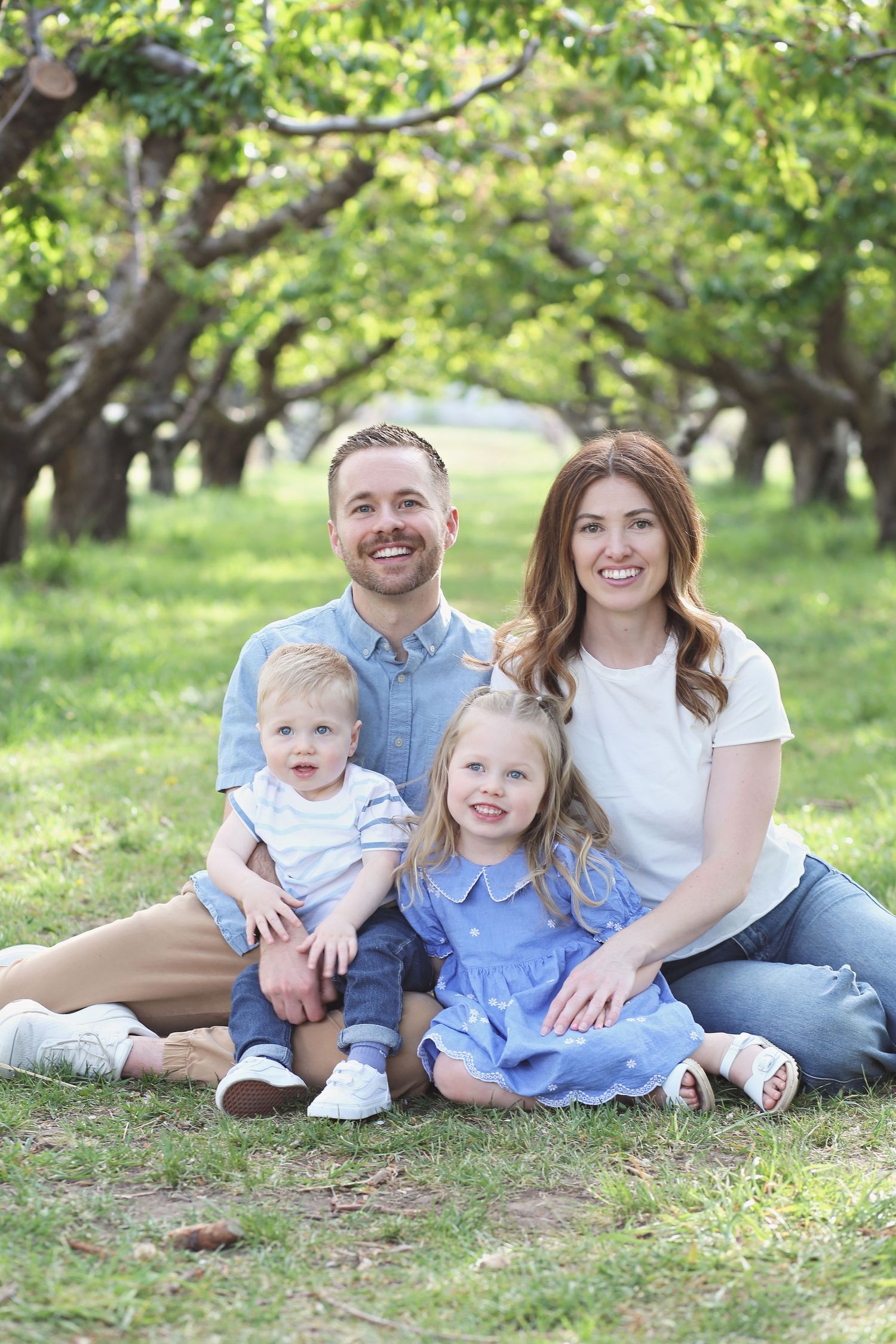 Family relaxing together on grass during an outdoor photo session.