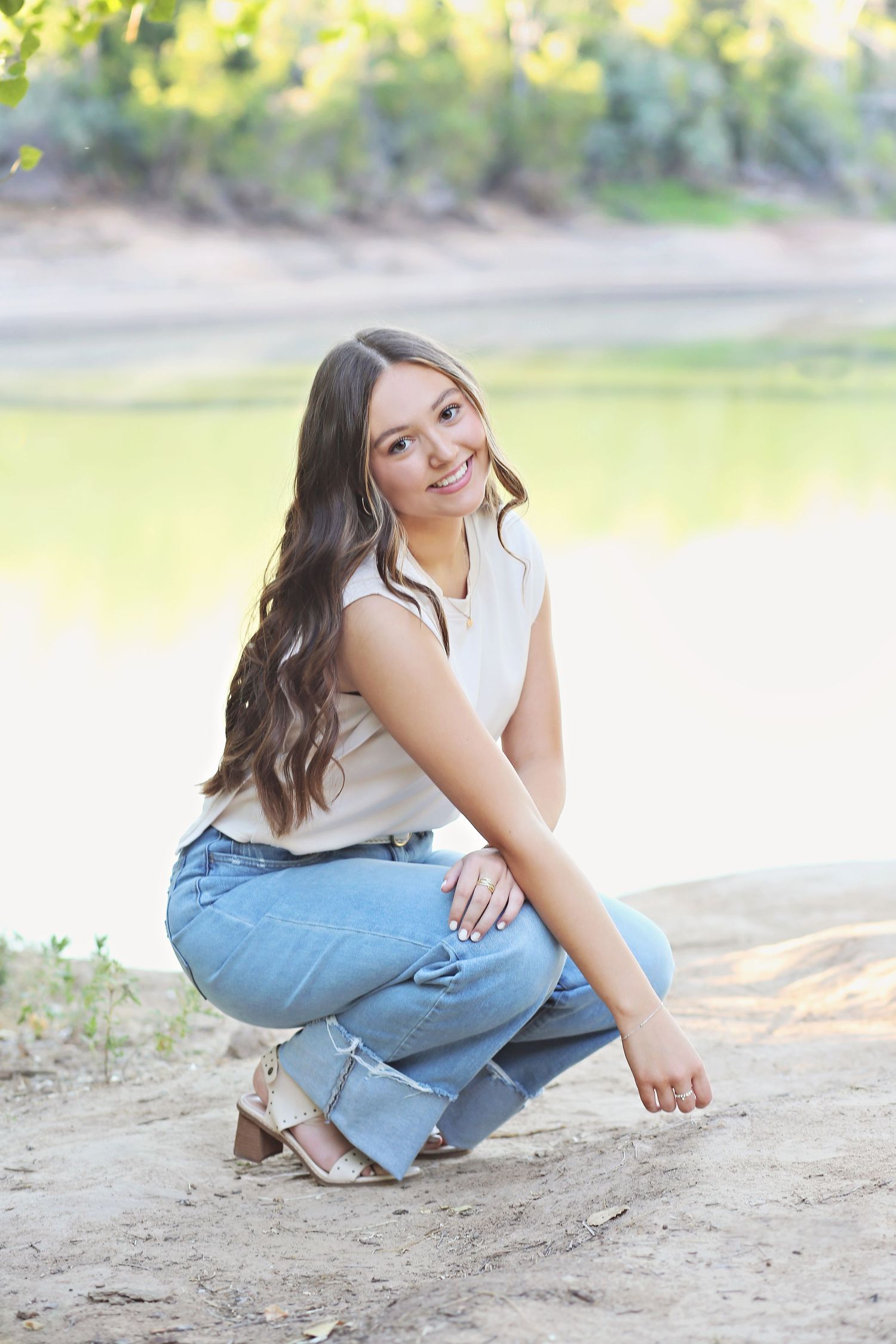 Casual outdoor portraits showing relaxed poses on sandy ground in jeans and white top.