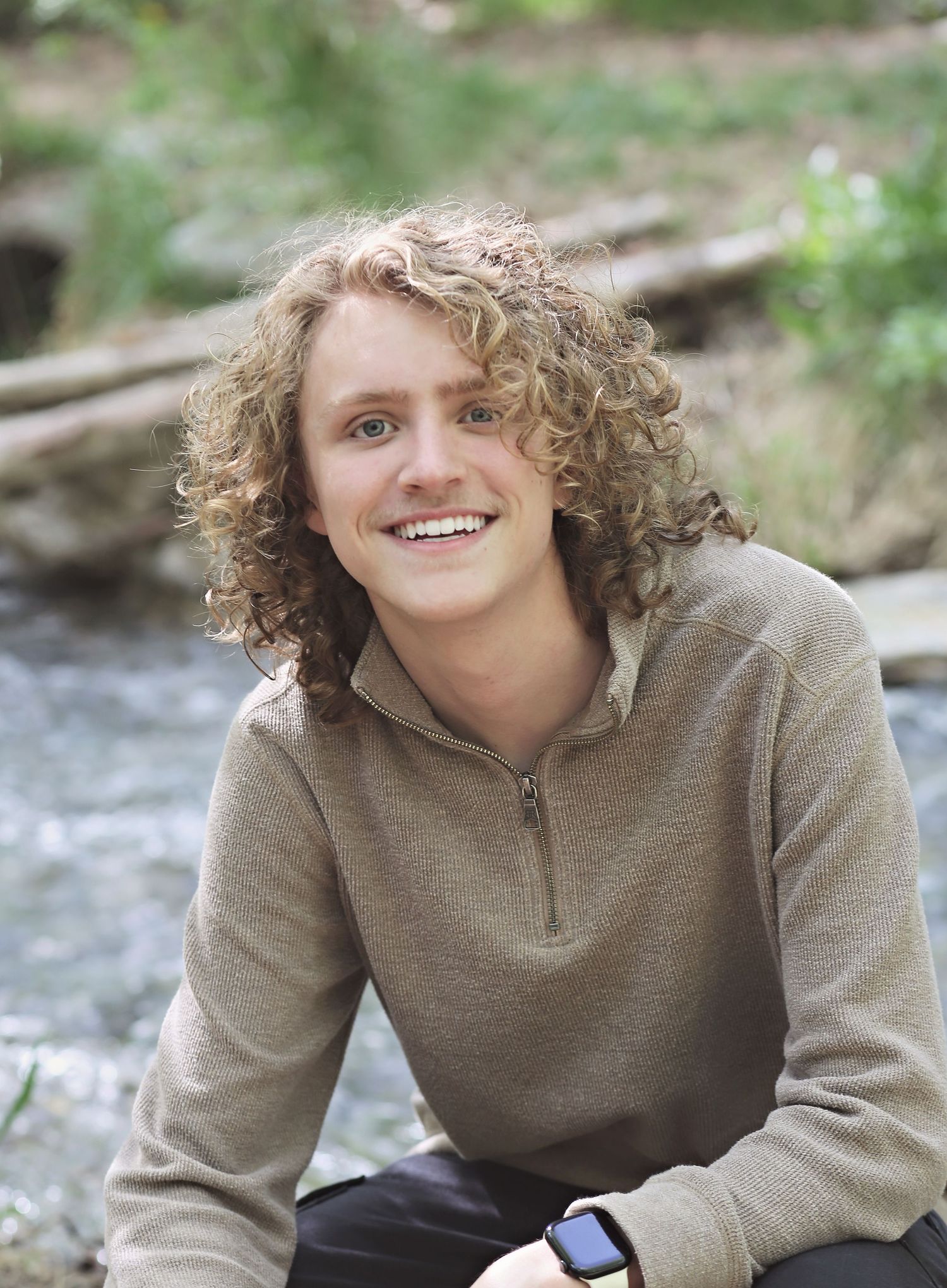 Outdoor portrait in natural setting wearing beige quarter-zip pullover.