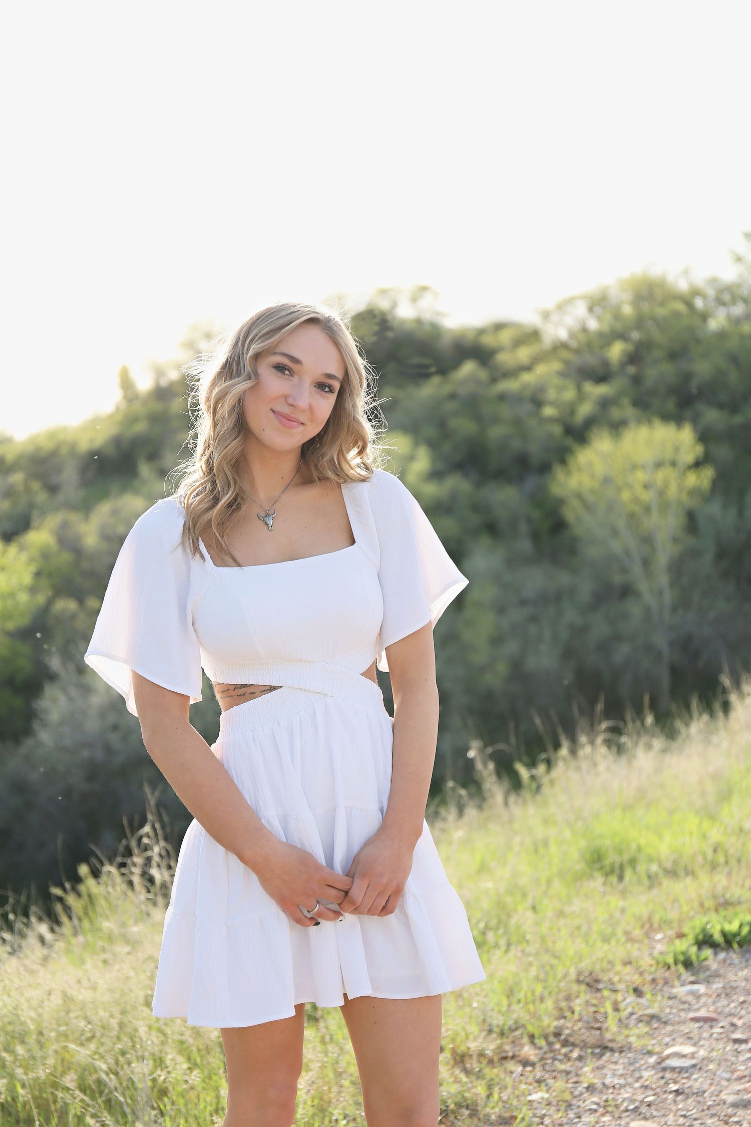 White summer dress portrait in golden hour lighting with natural backdrop.