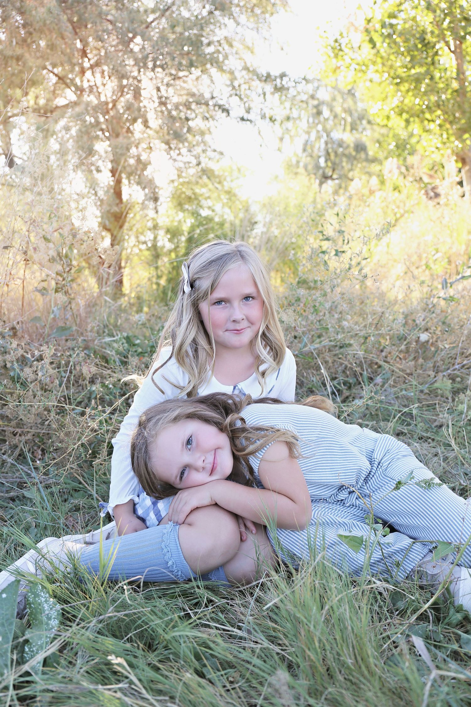 People lying in tall grass during a sunny outdoor photoshoot.