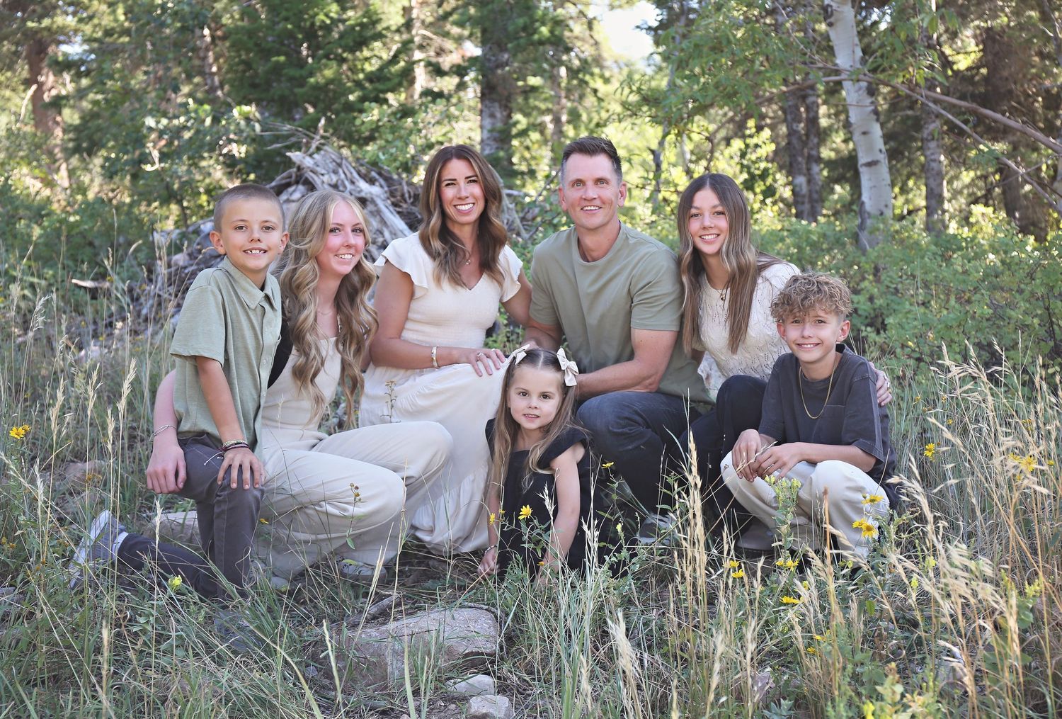 Family portrait outdoors in a natural setting with aspen trees and tall grass.