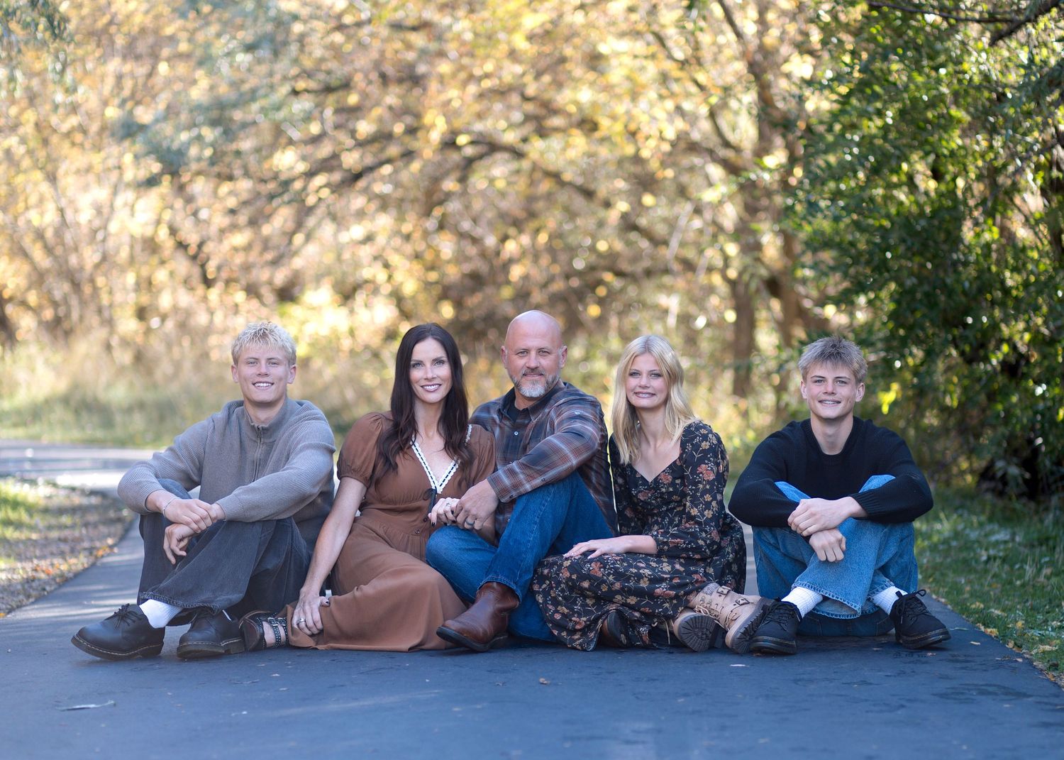 Family members lie casually on the ground for a relaxed outdoor portrait session.