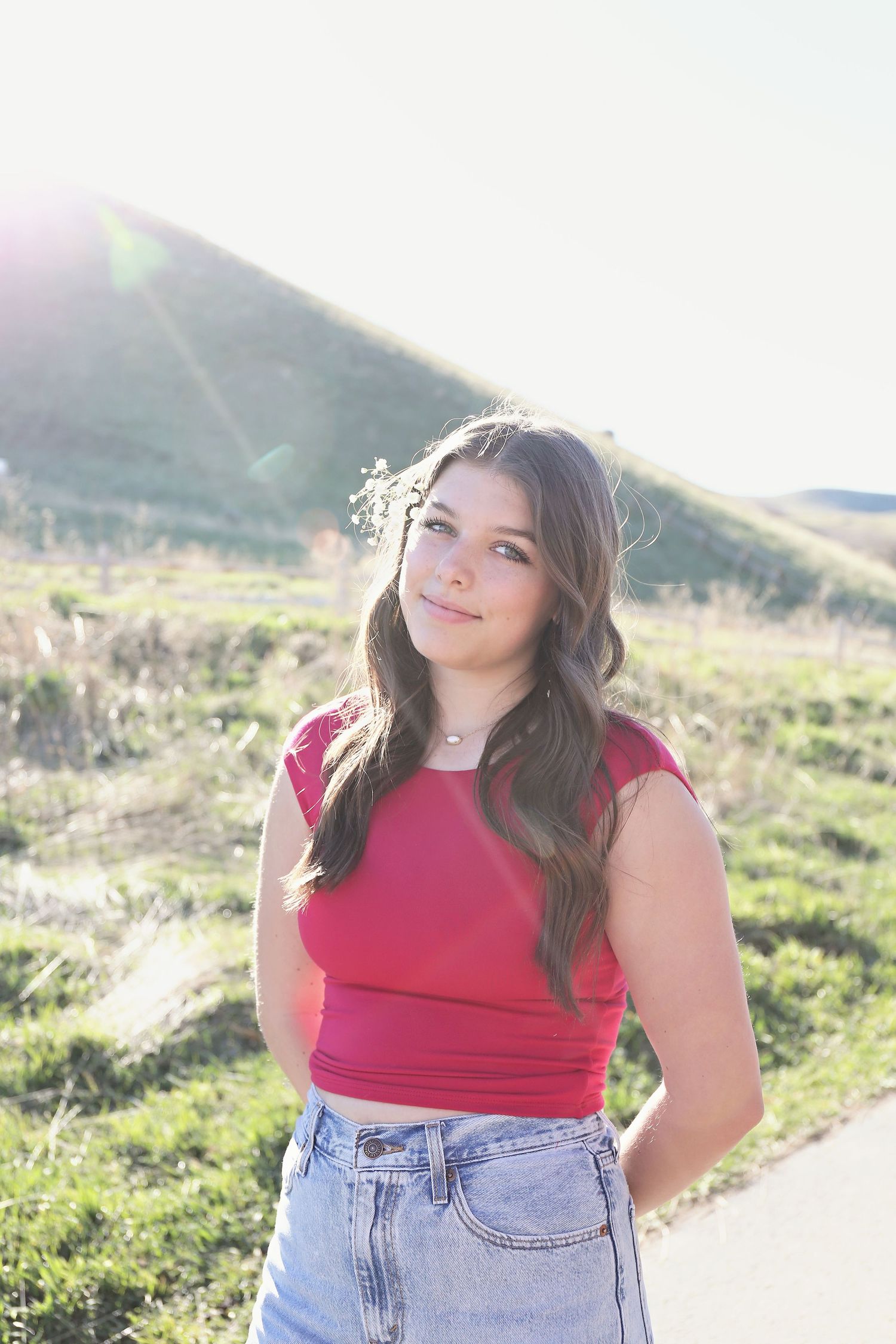 Red crop top and high-waisted jeans outfit captured in sunny outdoor setting.