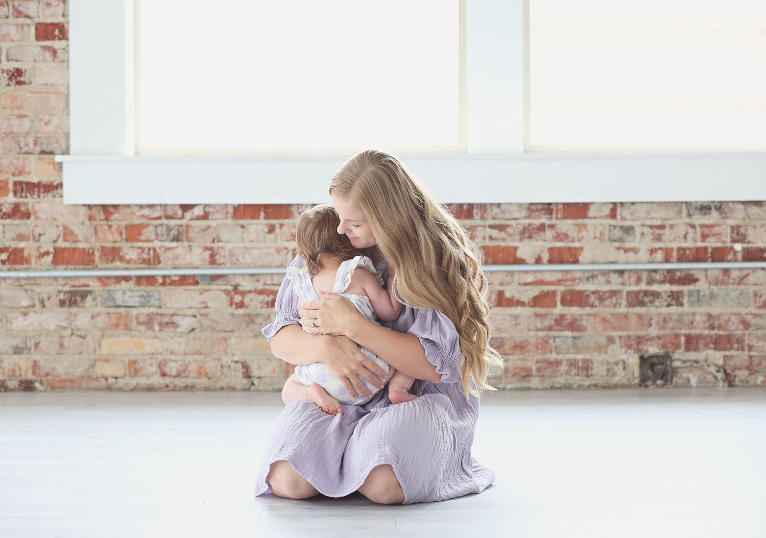 People embracing in matching outfits against a brick wall background.