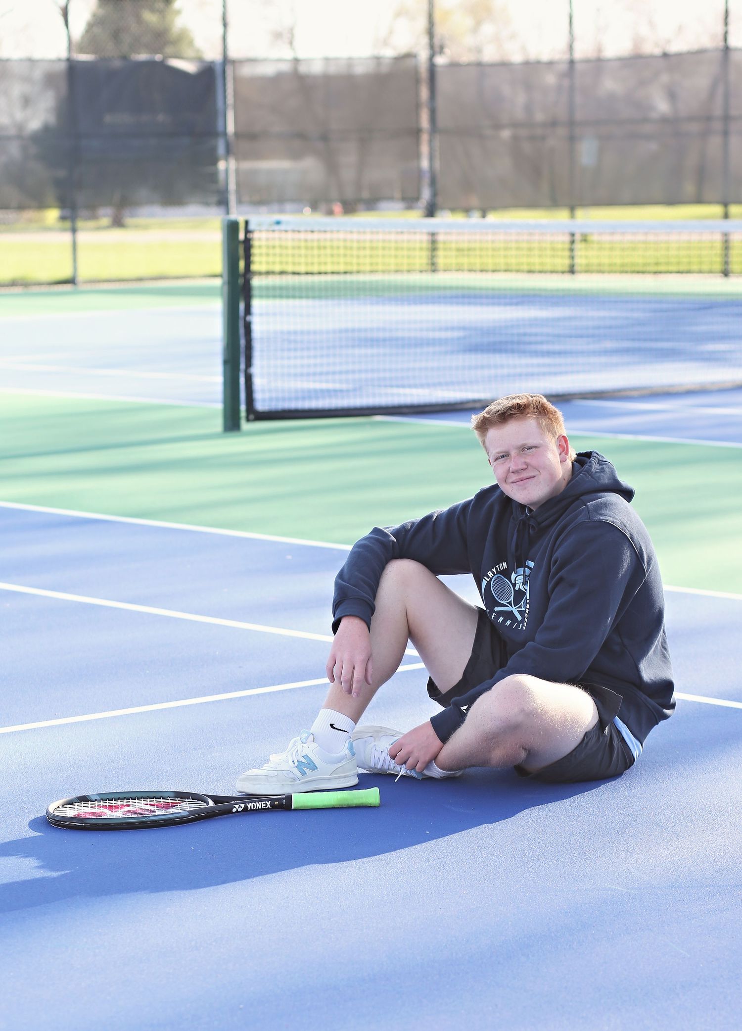 Tennis-themed photo shoot on blue courts with racket and athletic wear.
