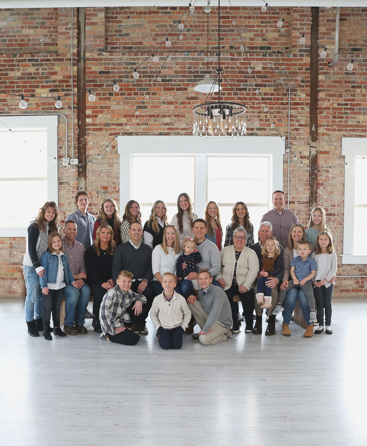 Large family gathering posed together in an industrial-style space with brick walls.