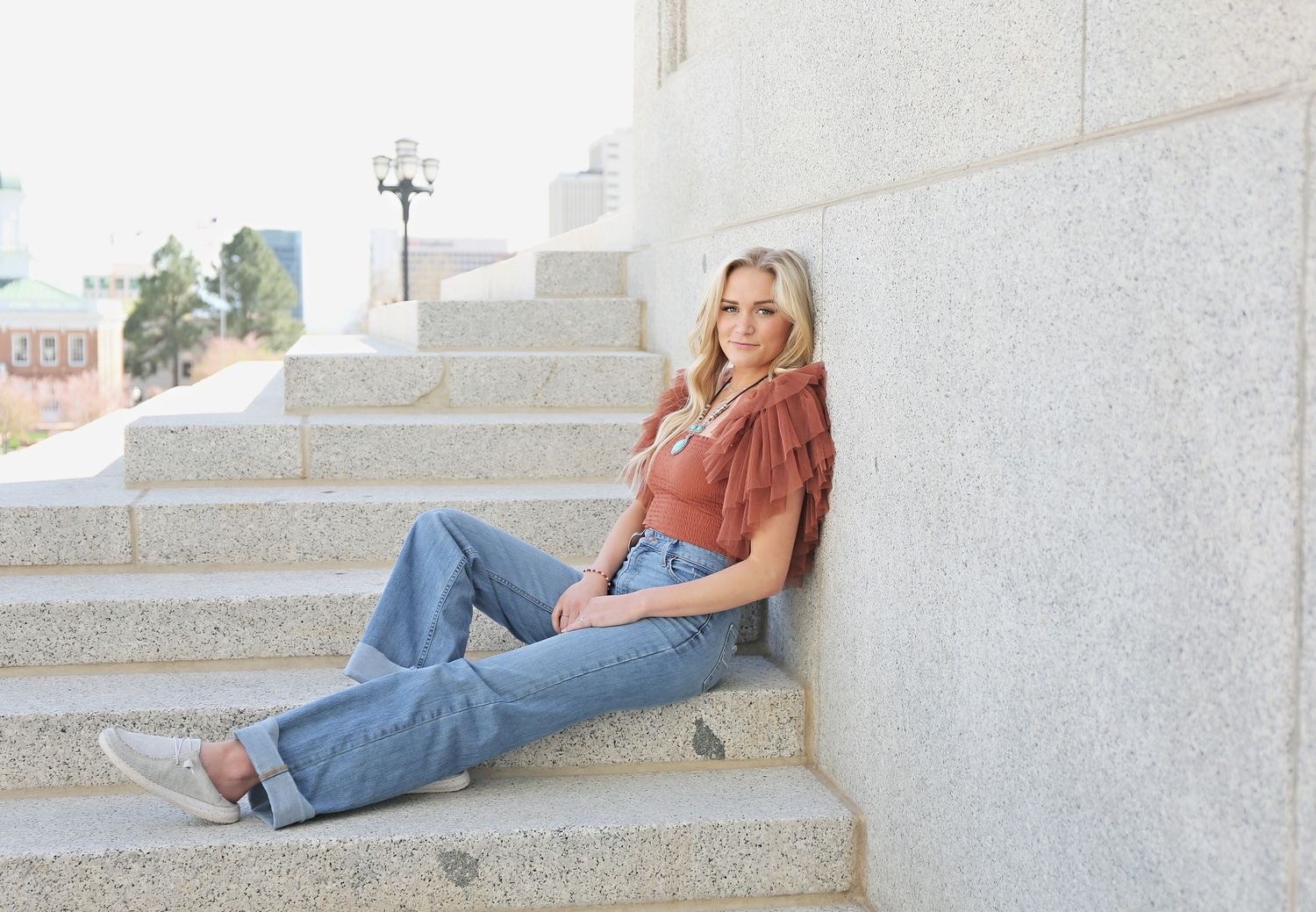 Person in casual attire reclining on white concrete steps outdoors.