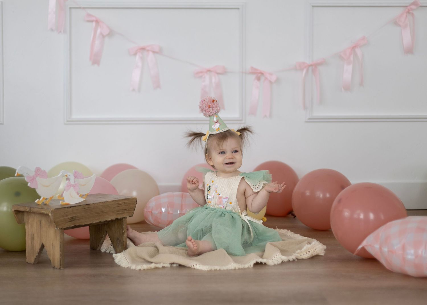 Pink and mint party decorations with balloons set up against a white backdrop.