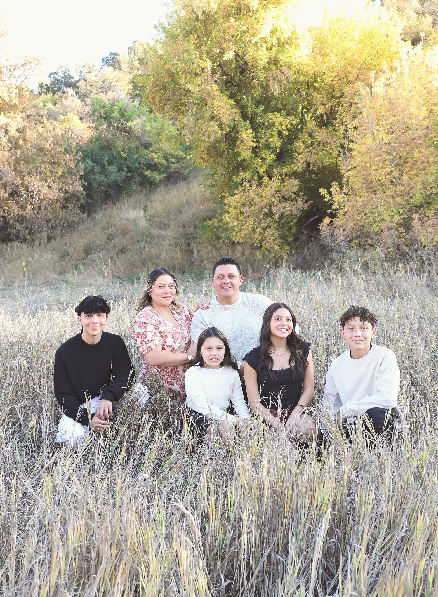 Group sitting together in a golden field during sunset with tall grass surrounding them.