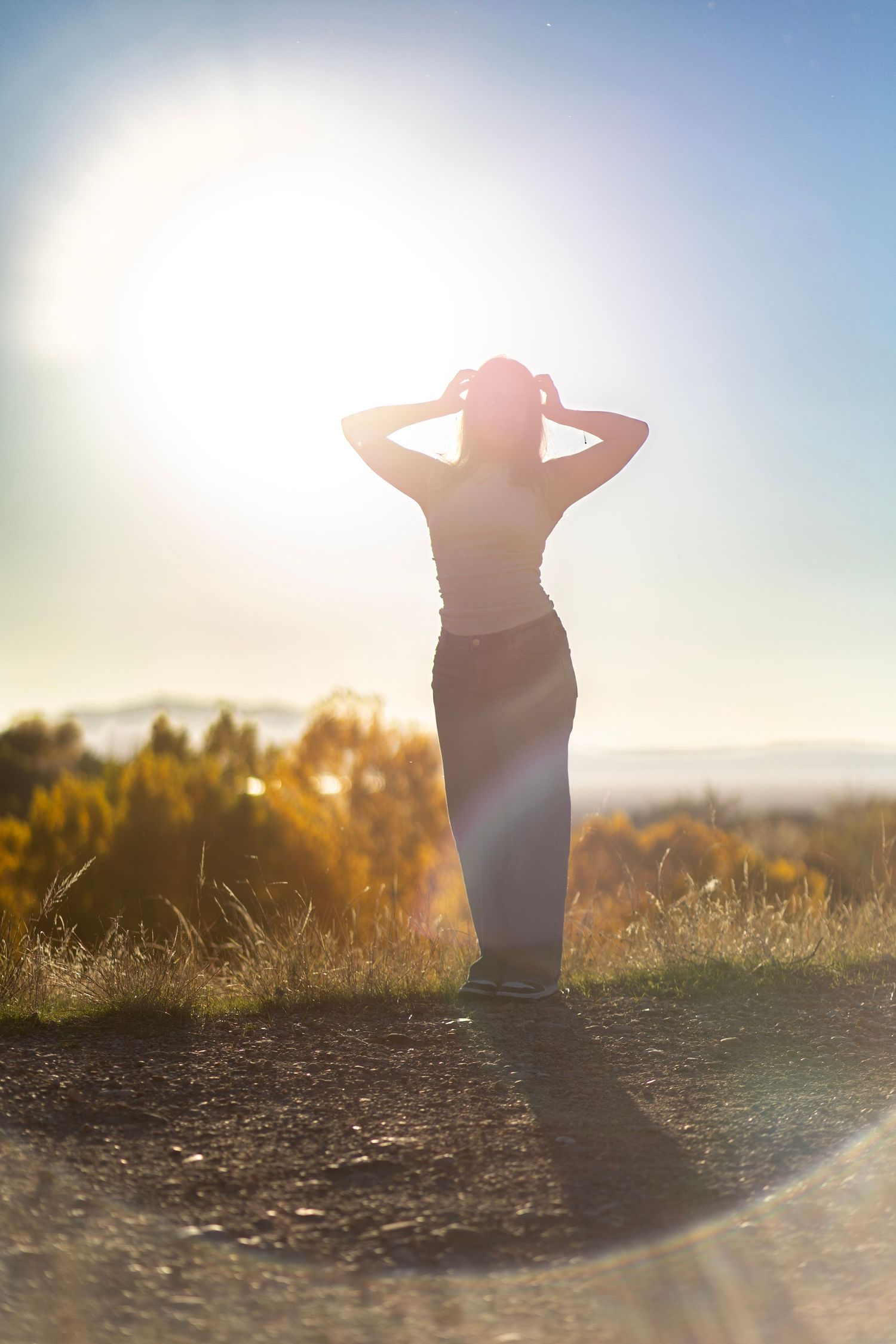 Silhouette of a person stretching with arms raised against golden sunset light in a grassy field.