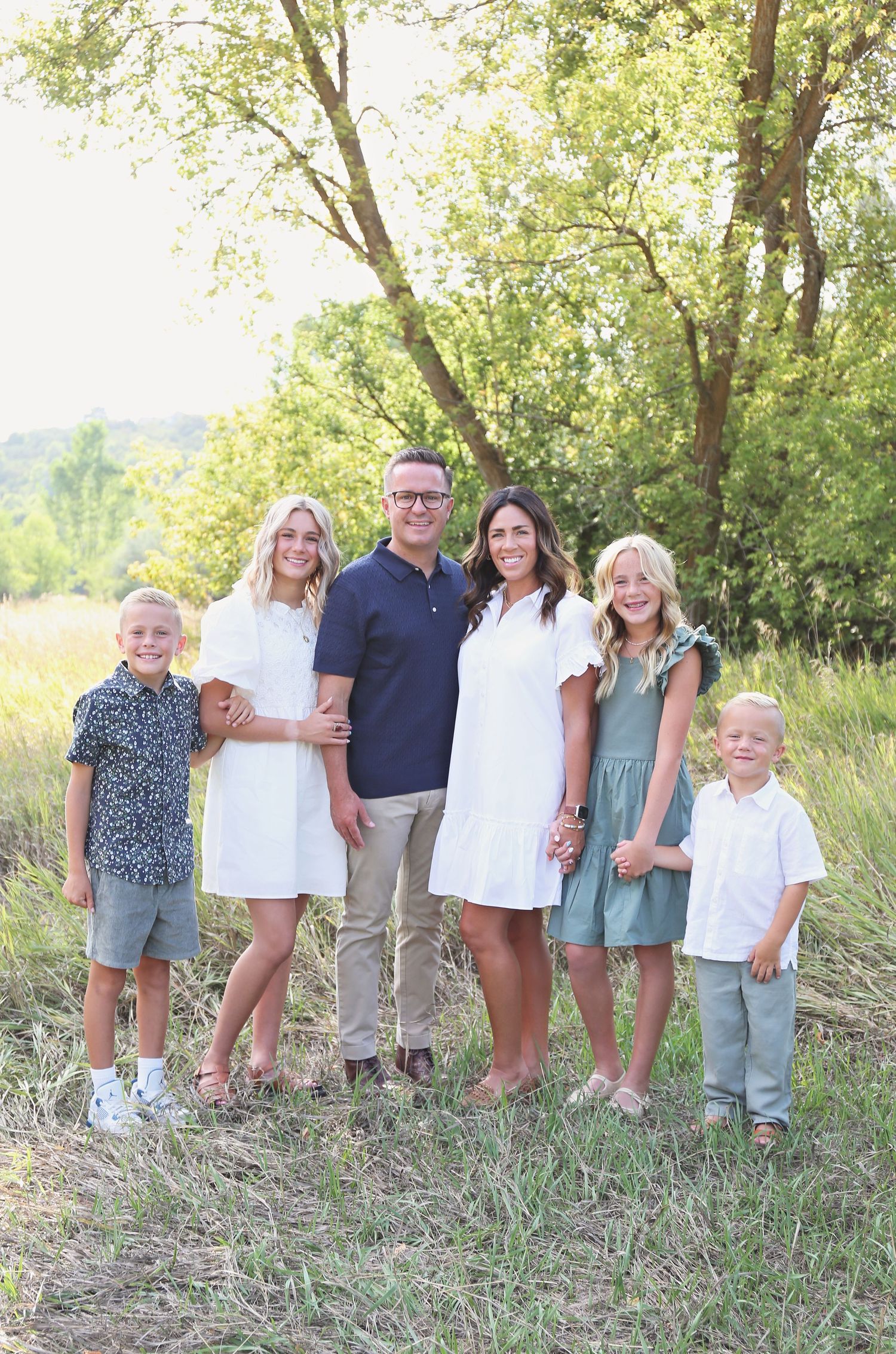 Extended family portrait session in natural outdoor setting with trees and grass.