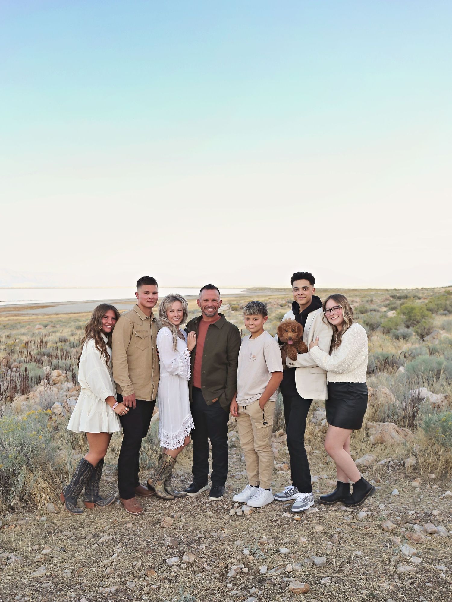 Extended family gathering for outdoor photos in desert setting with sagebrush and mountains.