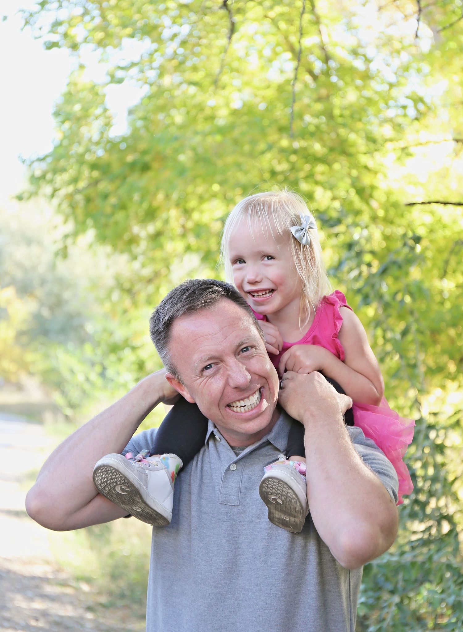Playful outdoor family moment with person in grey shirt and pink dress.