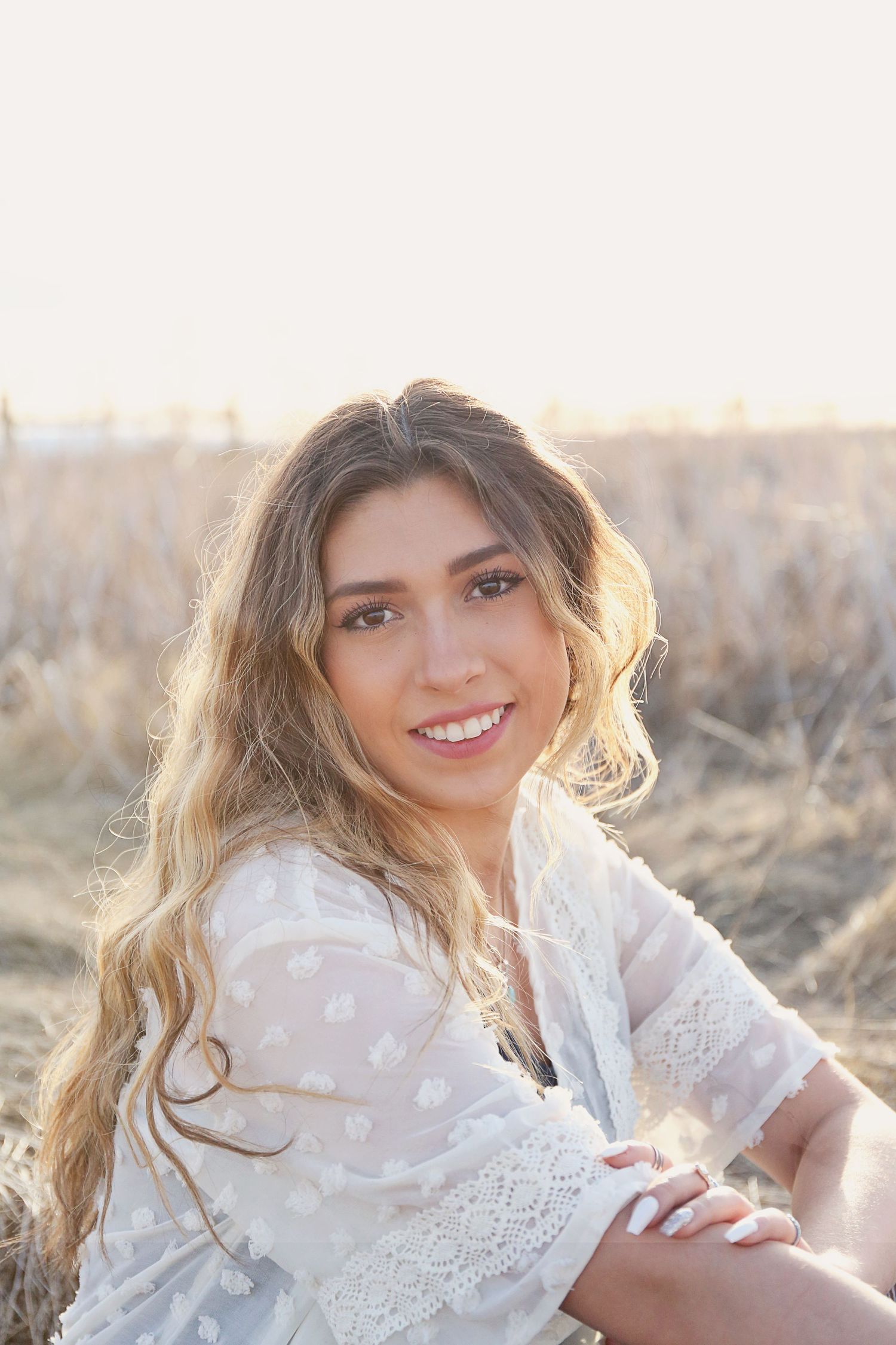 Delicate white lace dress photographed in golden sunlight against natural backdrop.