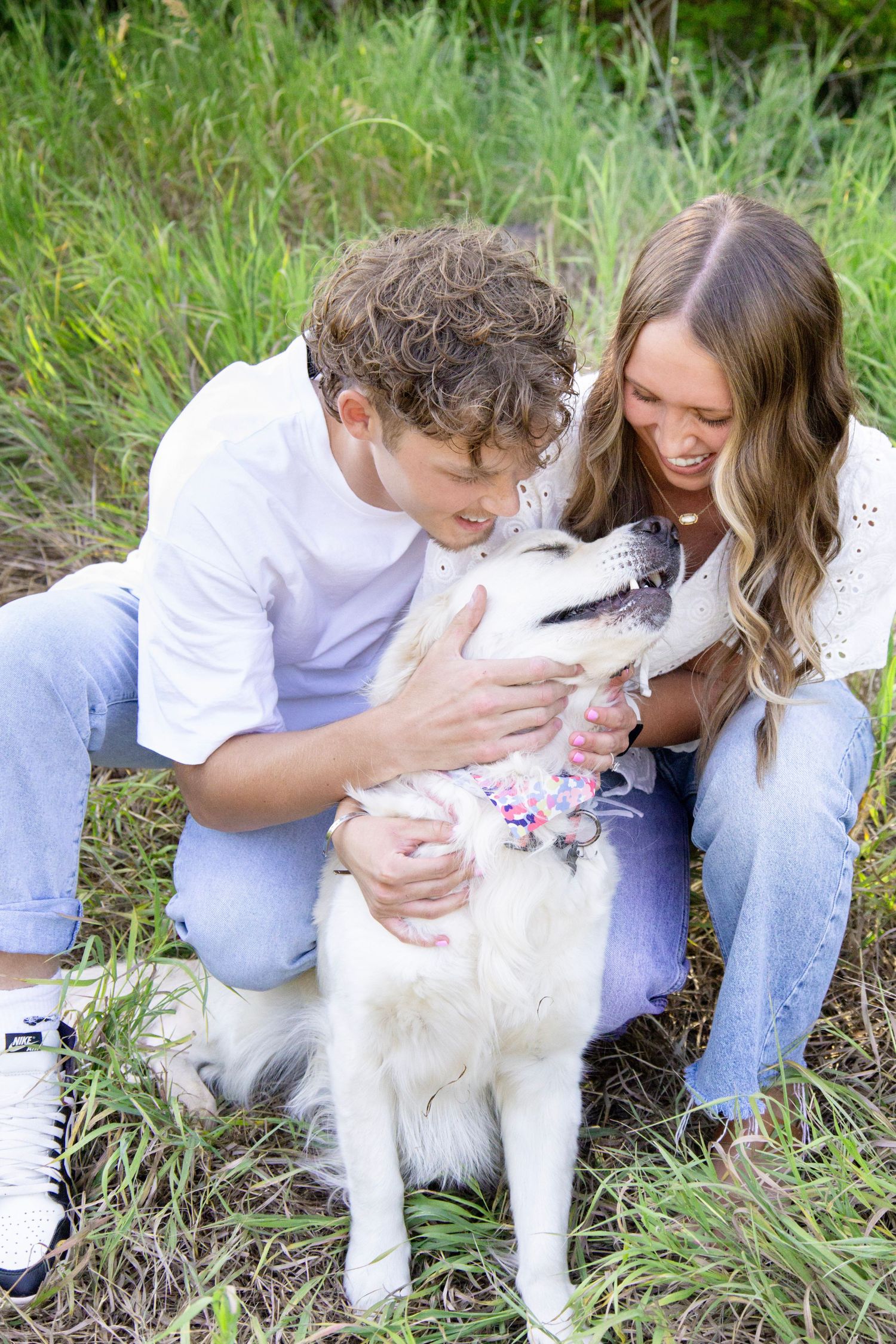 Playful moments with a fluffy white dog during outdoor pet photography session in tall grass.