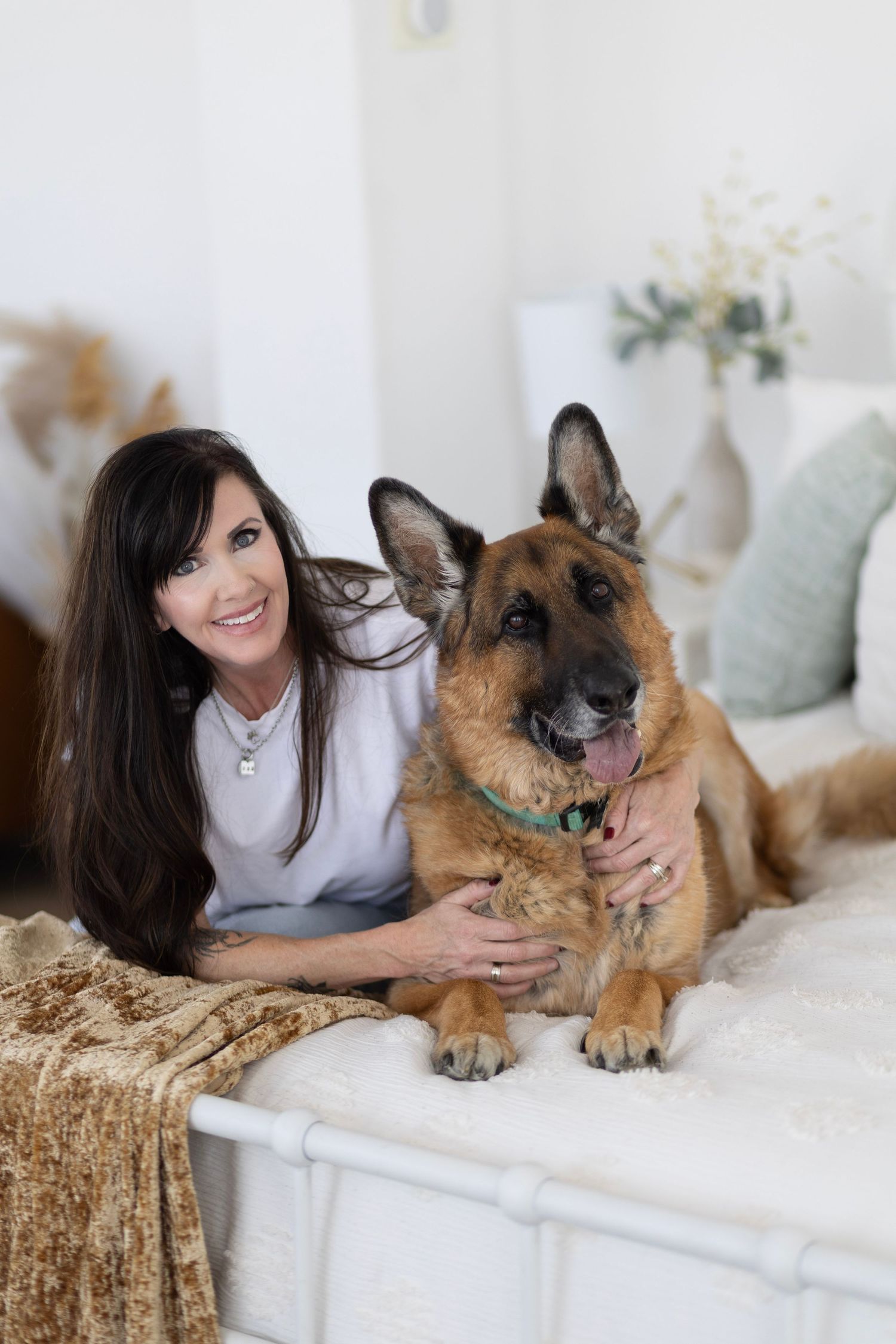 German Shepherd dog relaxes on white couch with companion in casual home setting.