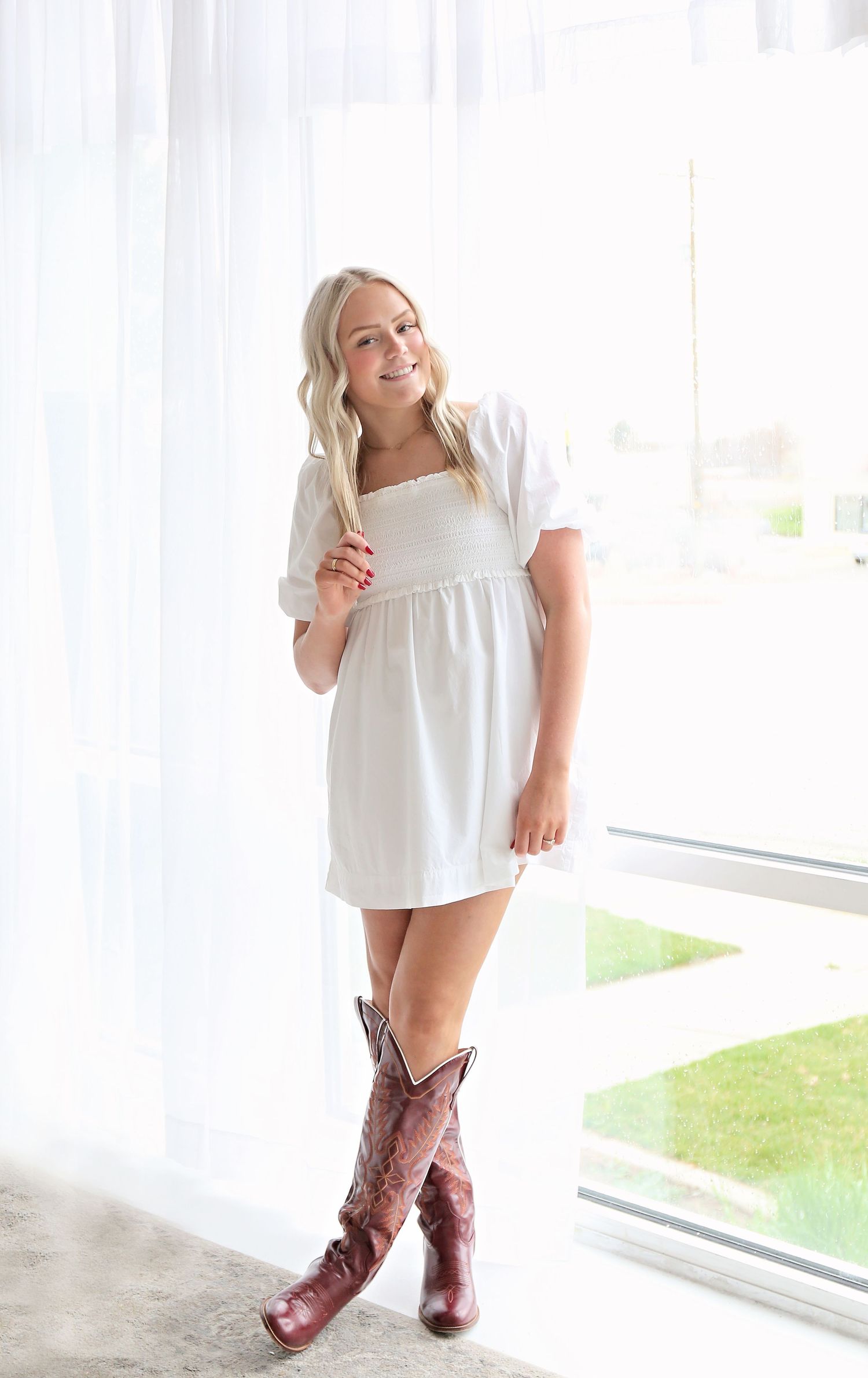 Brown cowboy boots paired with a flowing white top in a bright indoor setting.