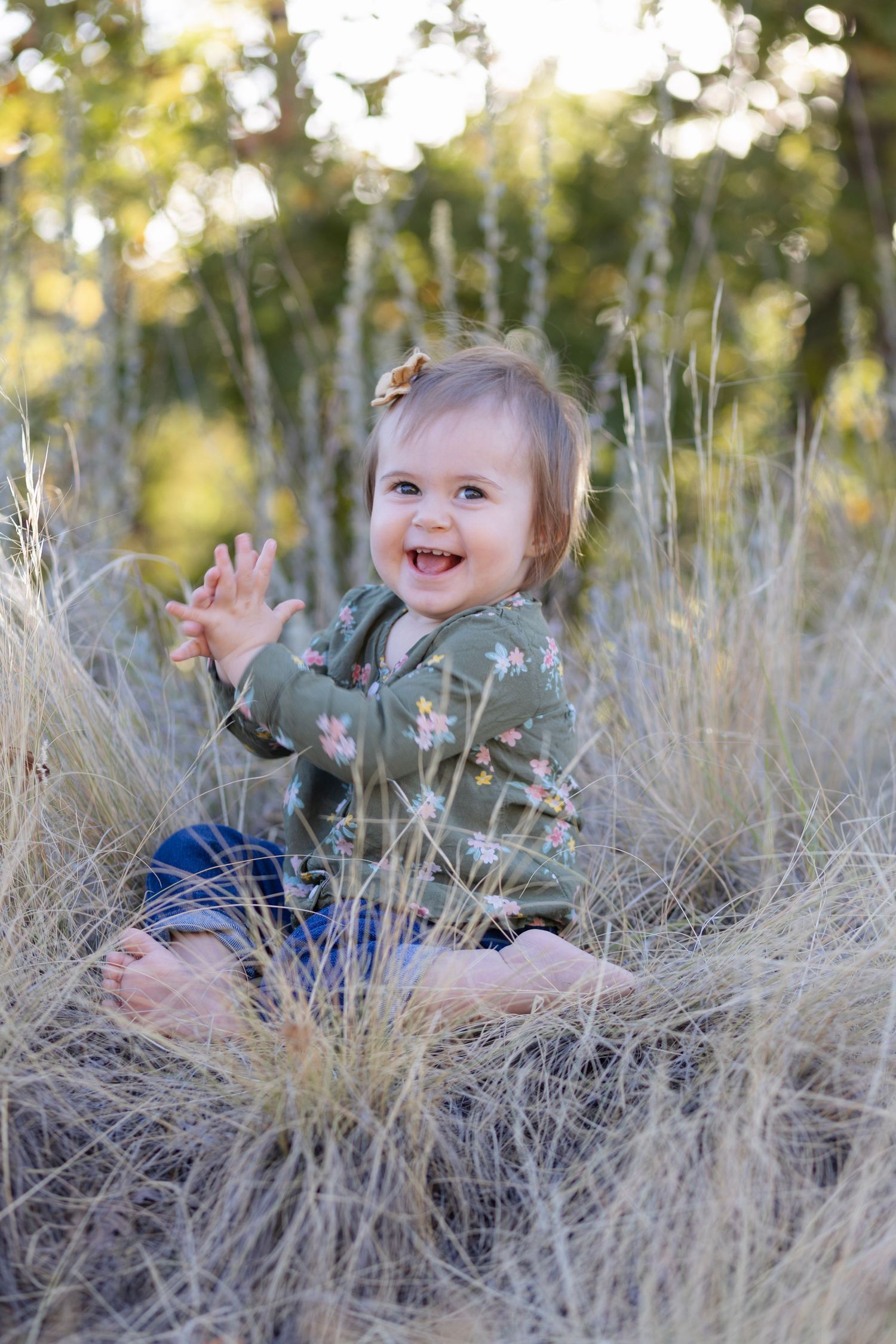 A child plays joyfully in tall dried grass during a golden hour photo session.