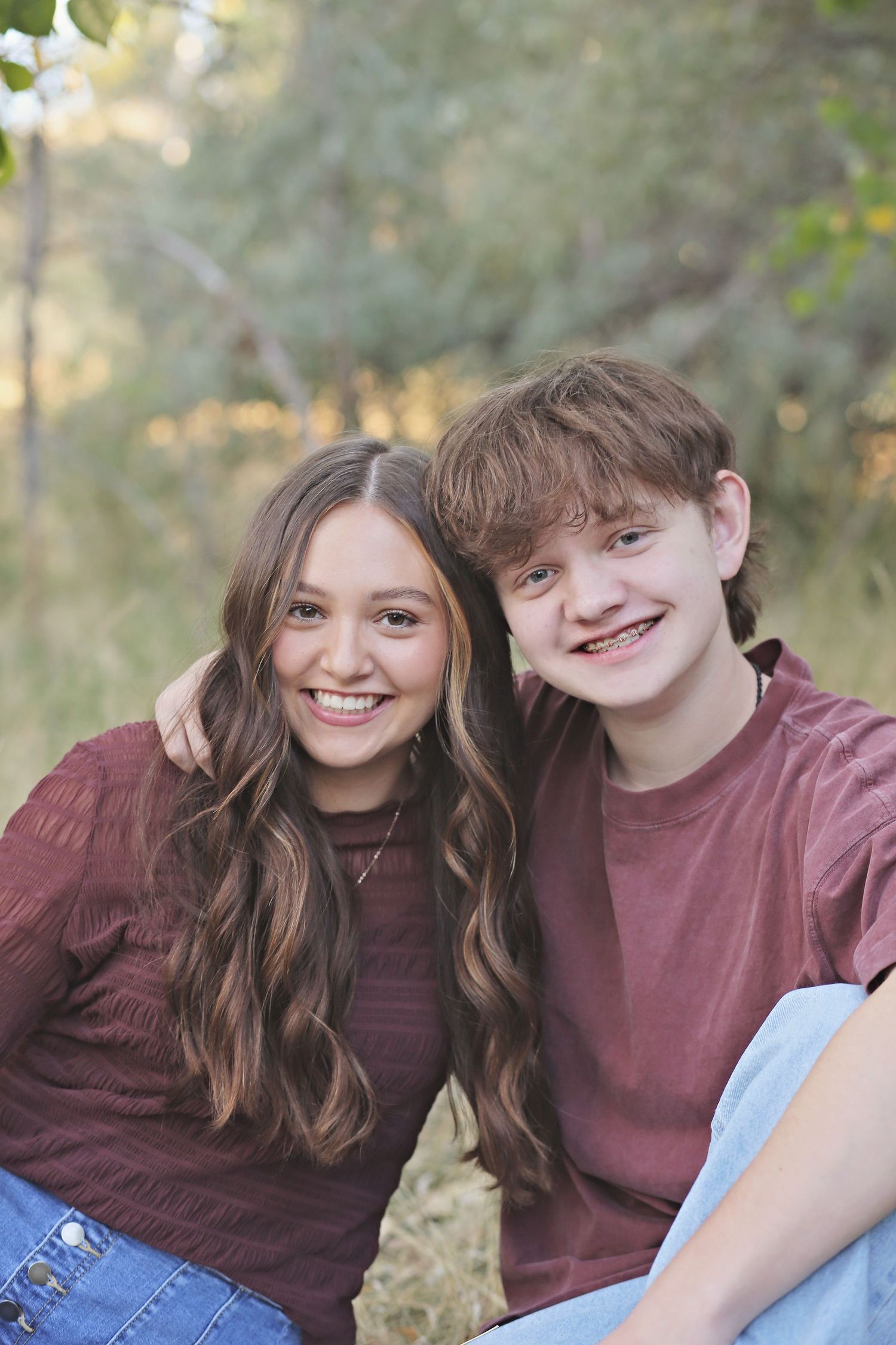 Two people in matching burgundy shirts share joyful moments outdoors.