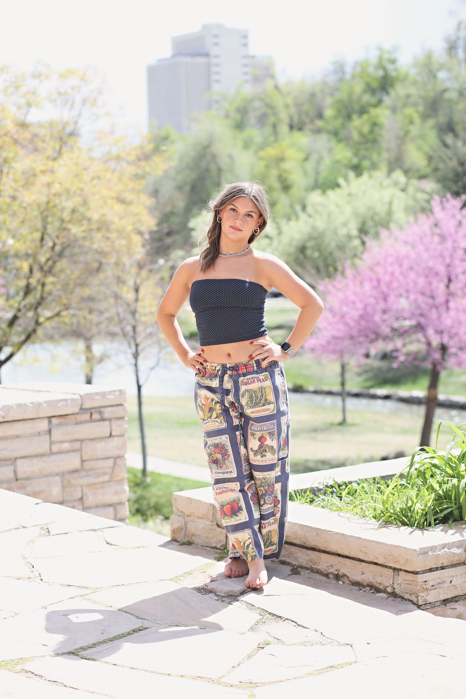 Casual outdoor photoshoot featuring patterned pants and a black crop top against stone architecture.