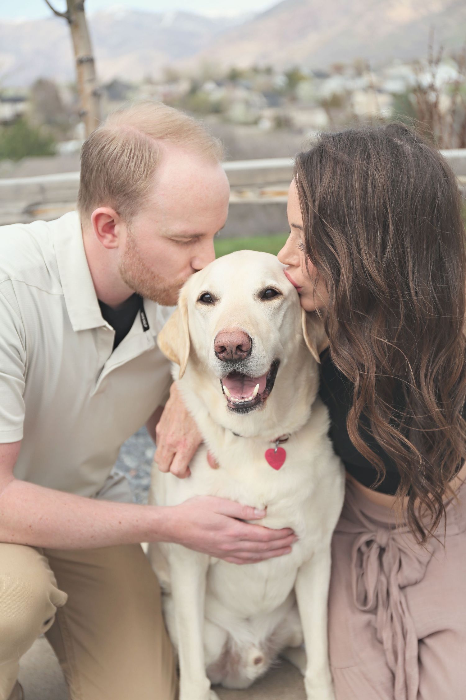 A happy cream-colored dog receives affection from its companions outdoors.