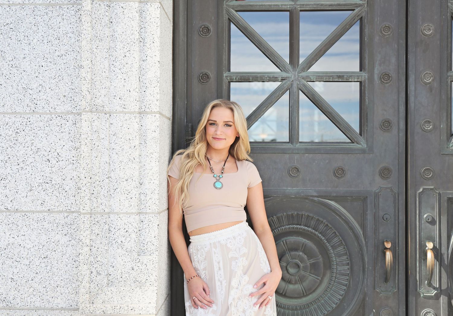 Four similar fashion photos showing someone posing in a white dress against an ornate stone building entrance.