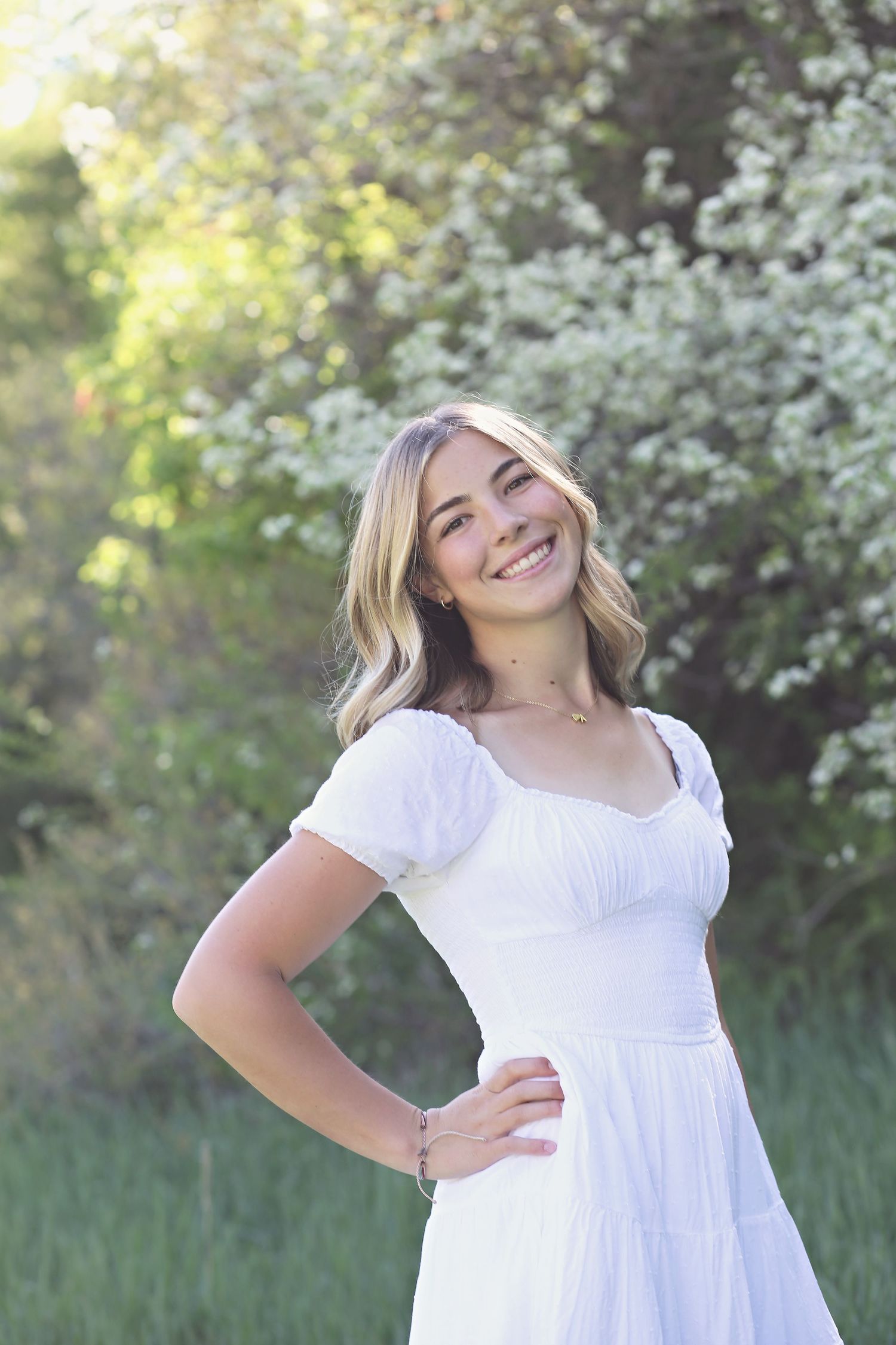 Outdoor spring portraits surrounded by blooming white flowers and natural sunlight.