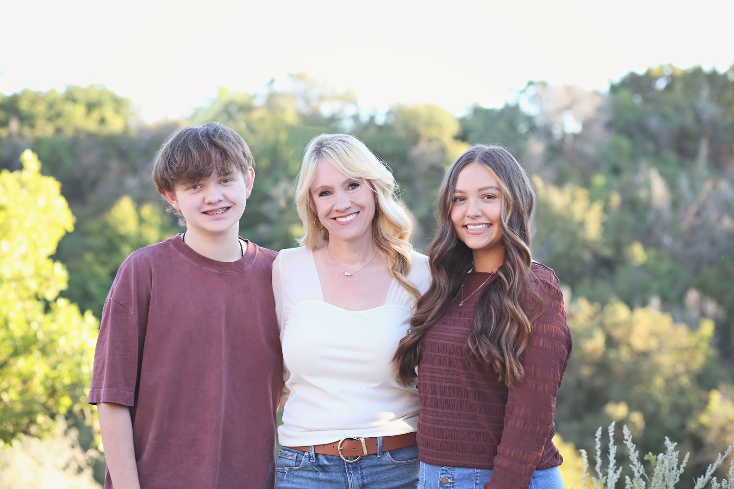 Group of people wearing burgundy and white tops posing together outdoors in natural lighting.