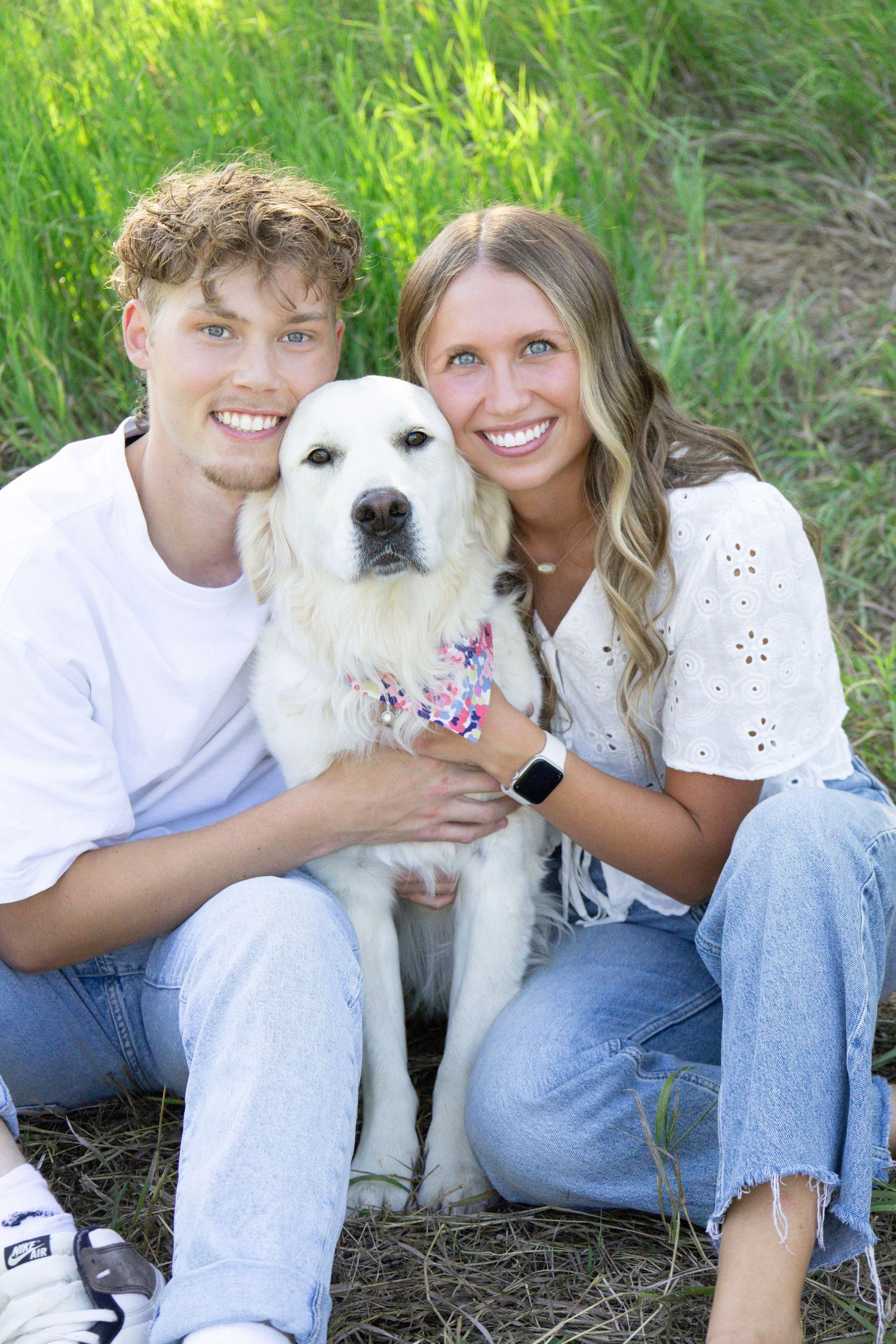 White dog posing with companions in casual summer outfits during outdoor photoshoot.