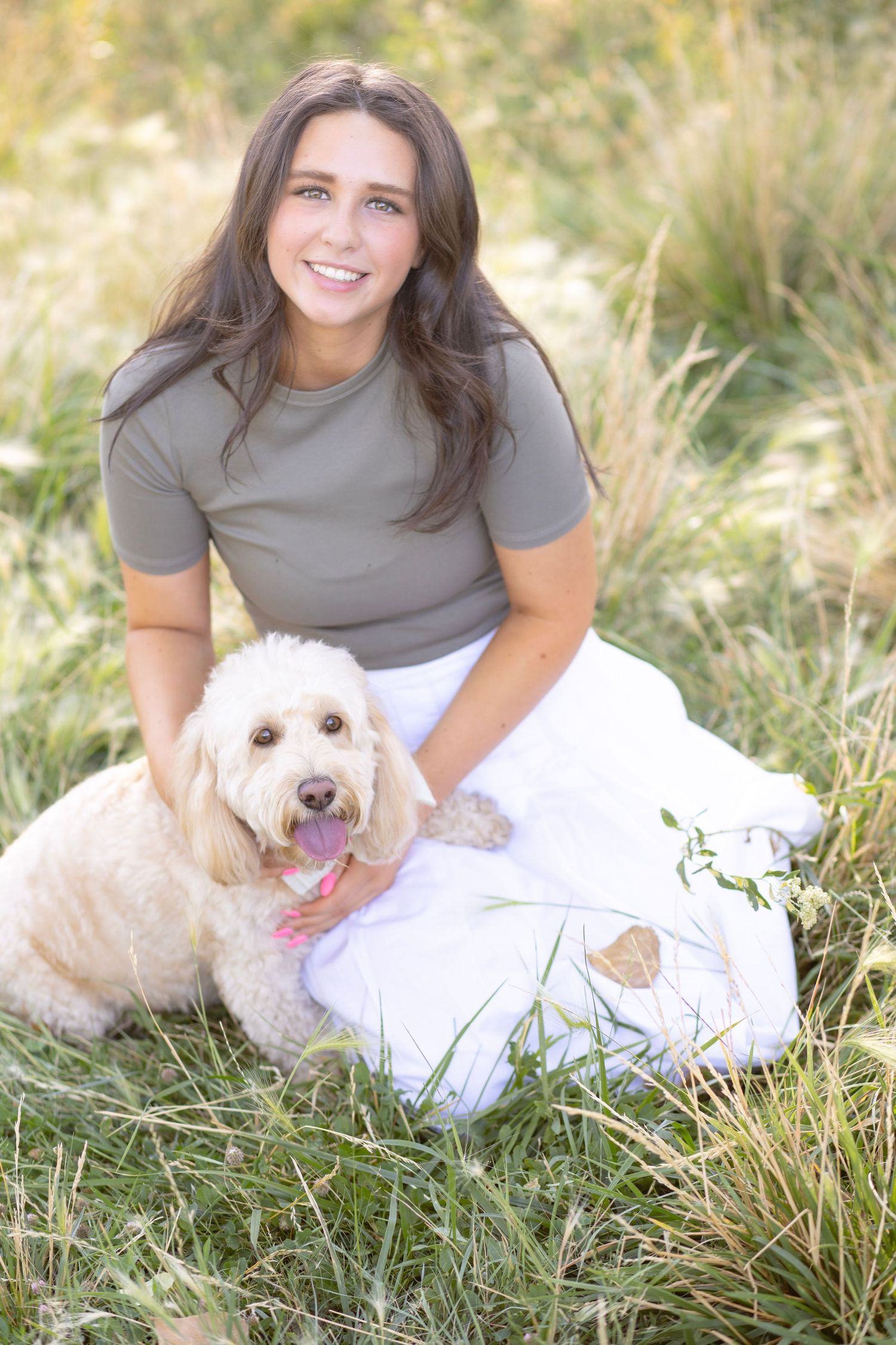 A casual outdoor portrait session with a person and their white fluffy dog in tall grass.