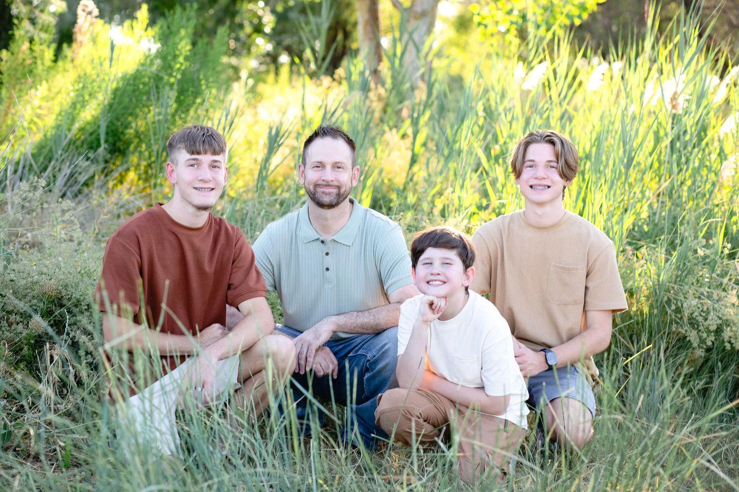 Group stands together in casual attire against a sunlit natural backdrop.