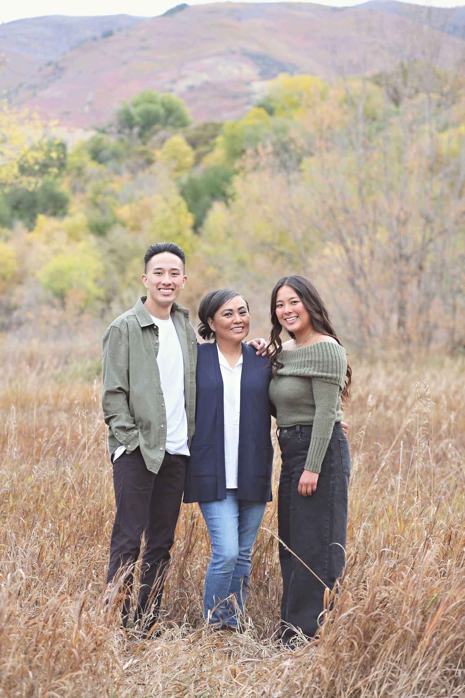 Group photo in tall grass with mountains and autumn foliage creating a natural backdrop.