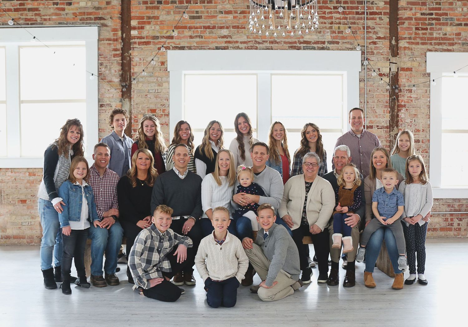 Large group portrait of multiple generations in a rustic brick-walled room.