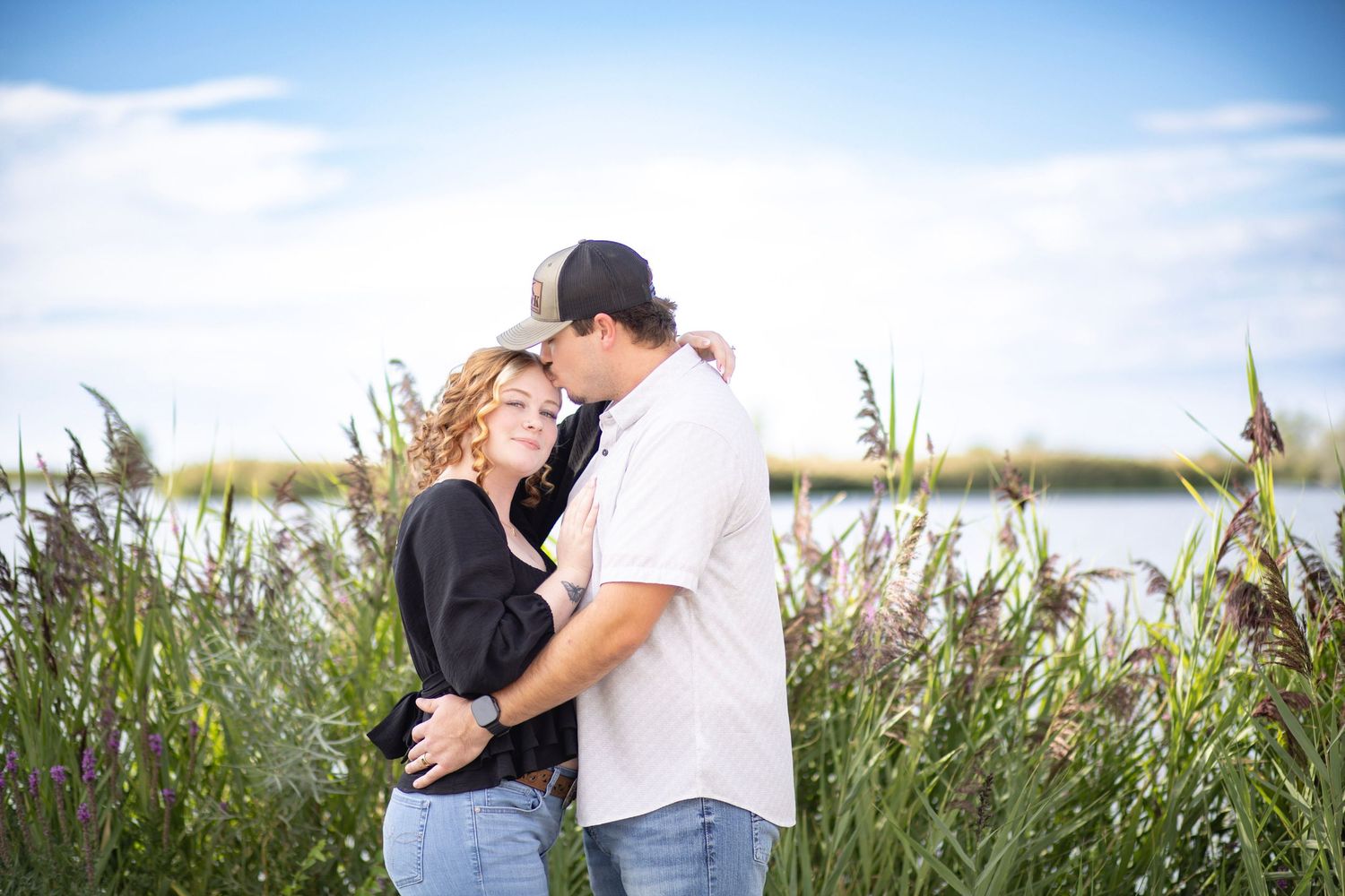 Romantic photoshoot in field with tall grass and blue sky background.