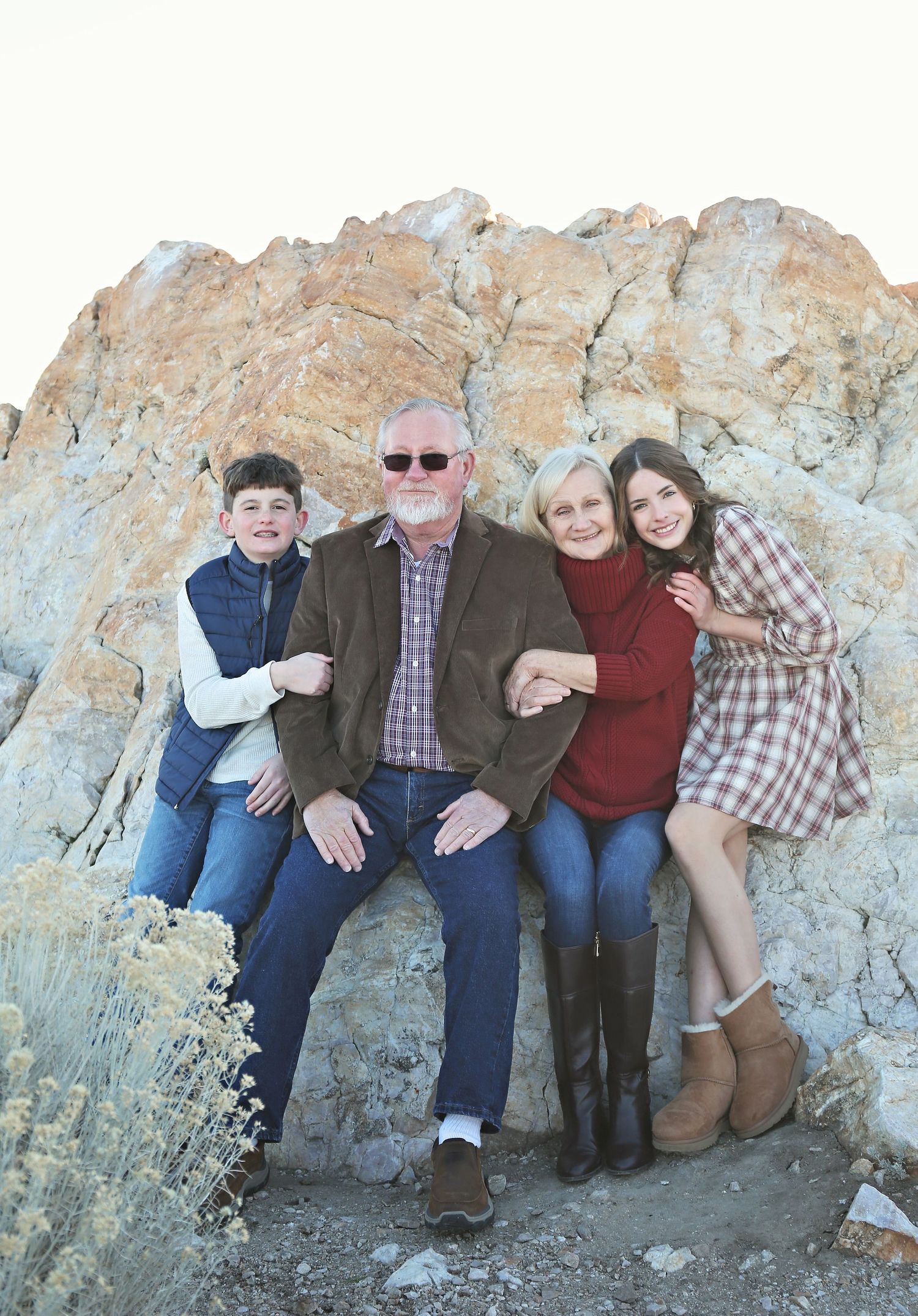 Multi-generational group photo against large rock formations in desert landscape.