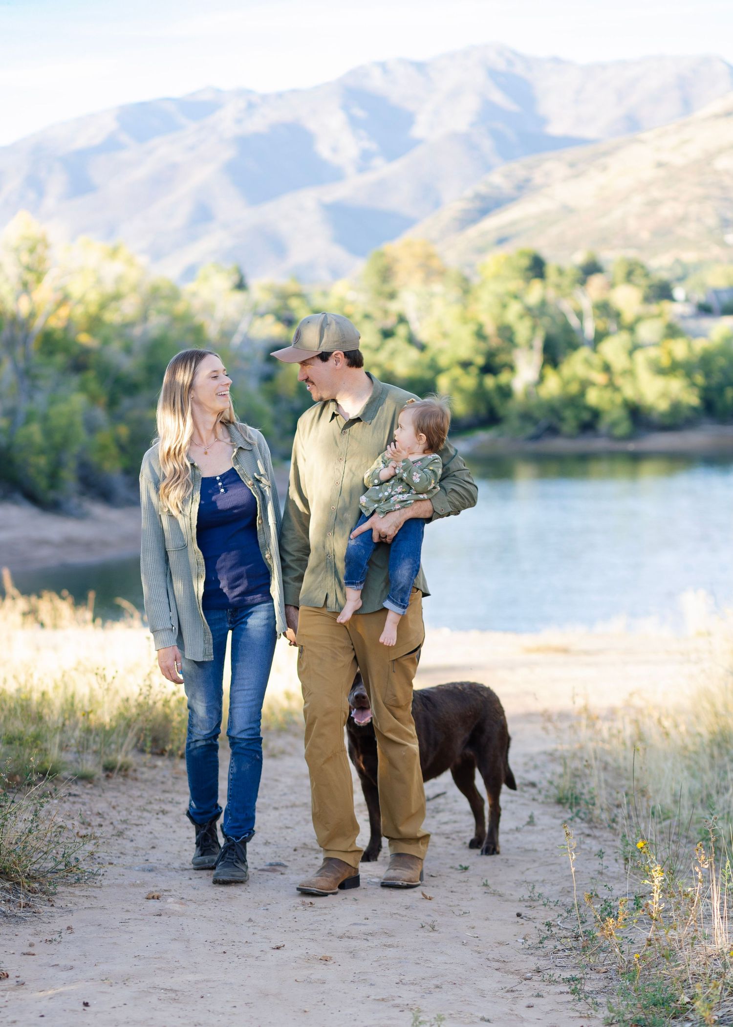 Family portrait session by mountain lake with chocolate lab dog in autumn setting.