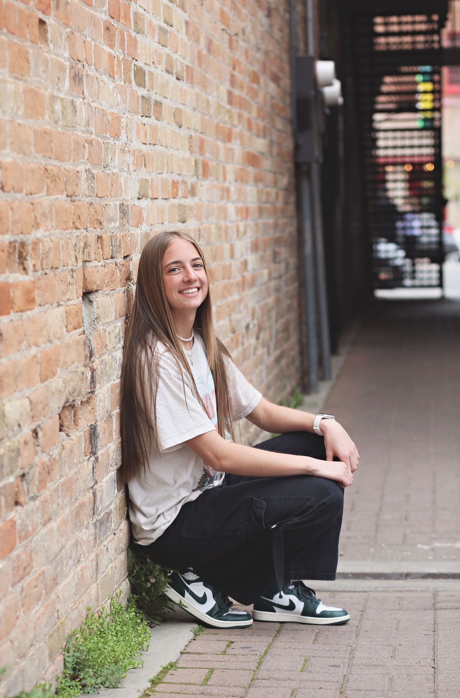 Casual street photography along brick walls wearing white shirt and black pants.