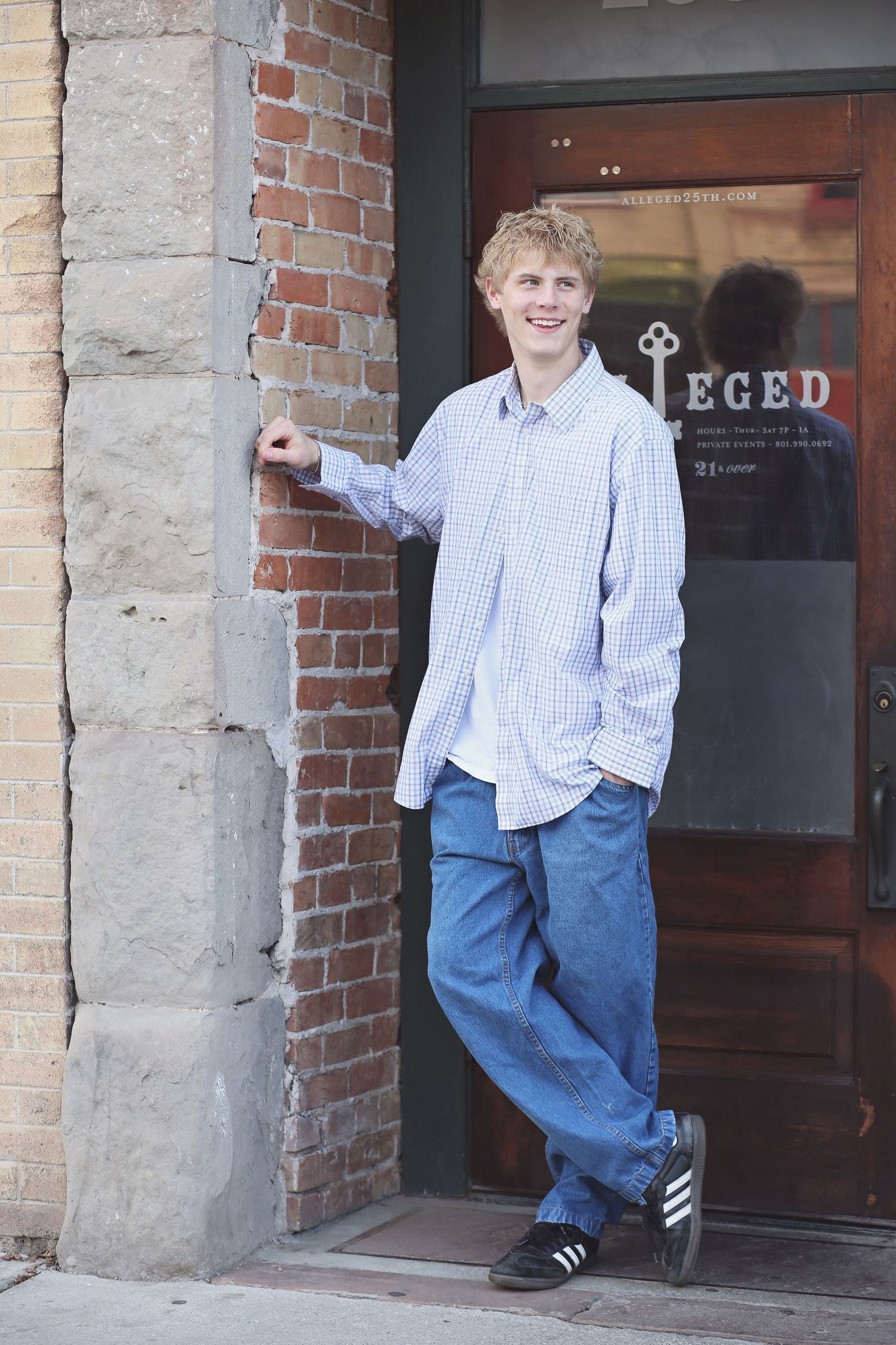 Casual portraits against a brick building entrance with someone in a checkered shirt and jeans.