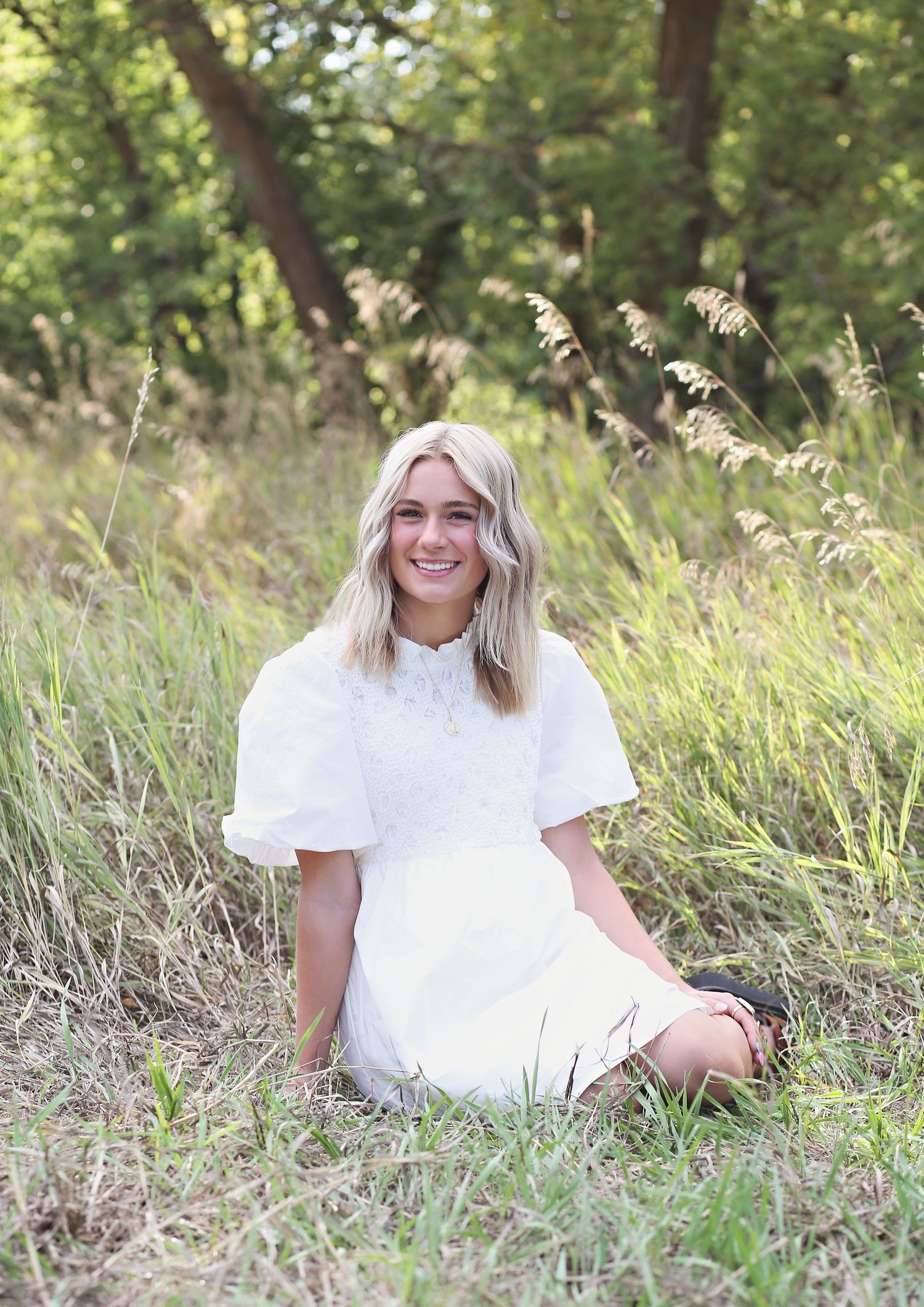 Portrait session in tall grass with natural lighting and white shirt creating a bright summer mood.